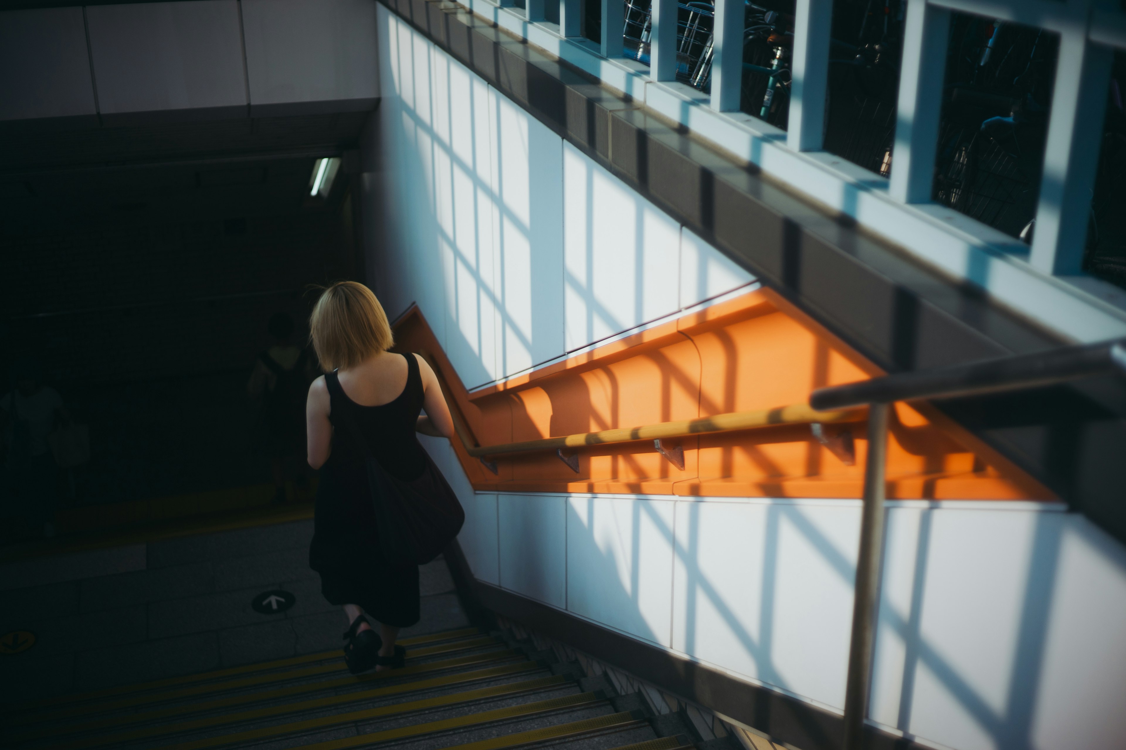 Donna che scende le scale con la luce del sole che proietta ombre