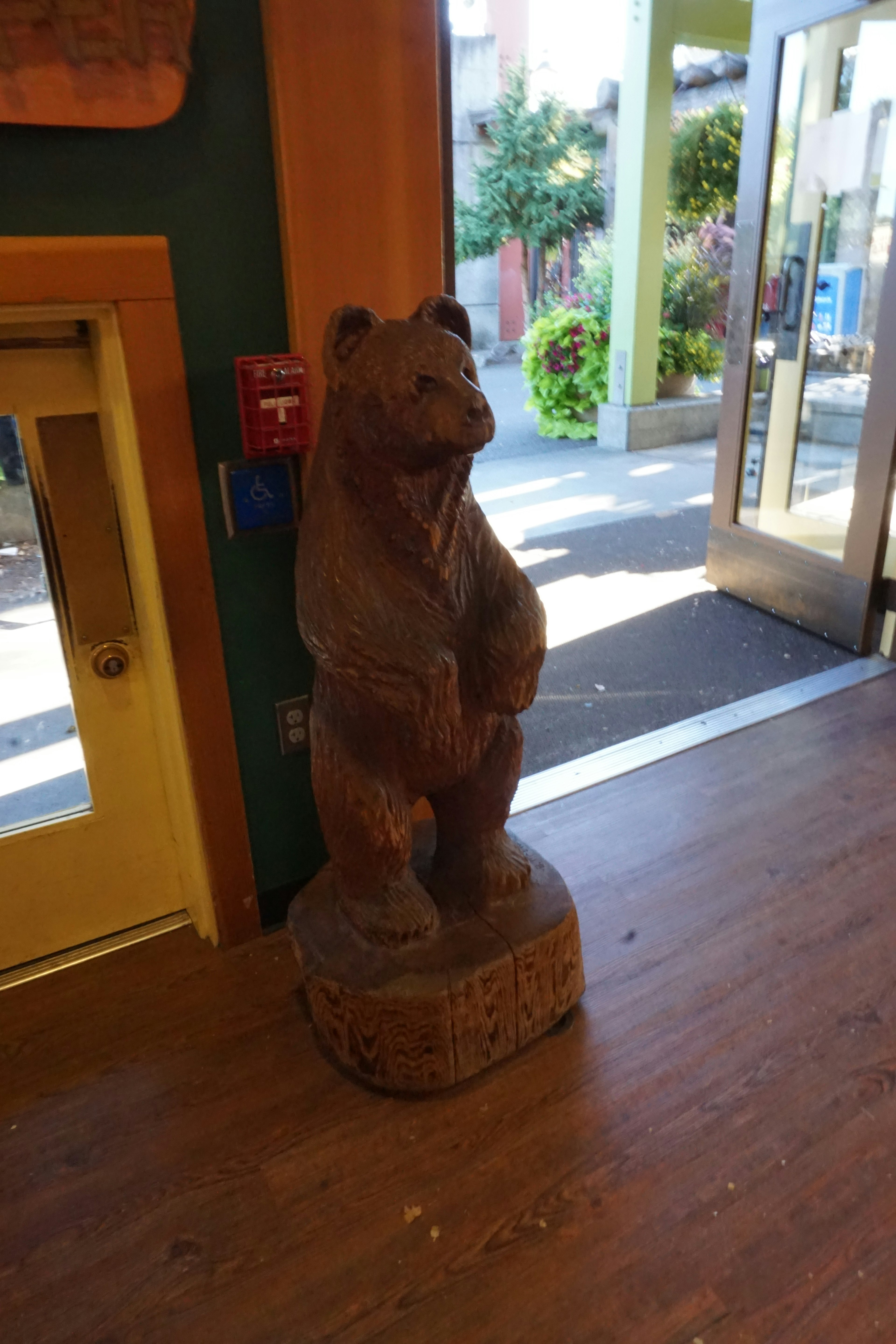 Escultura de madera de un oso de pie dentro de la entrada de una tienda