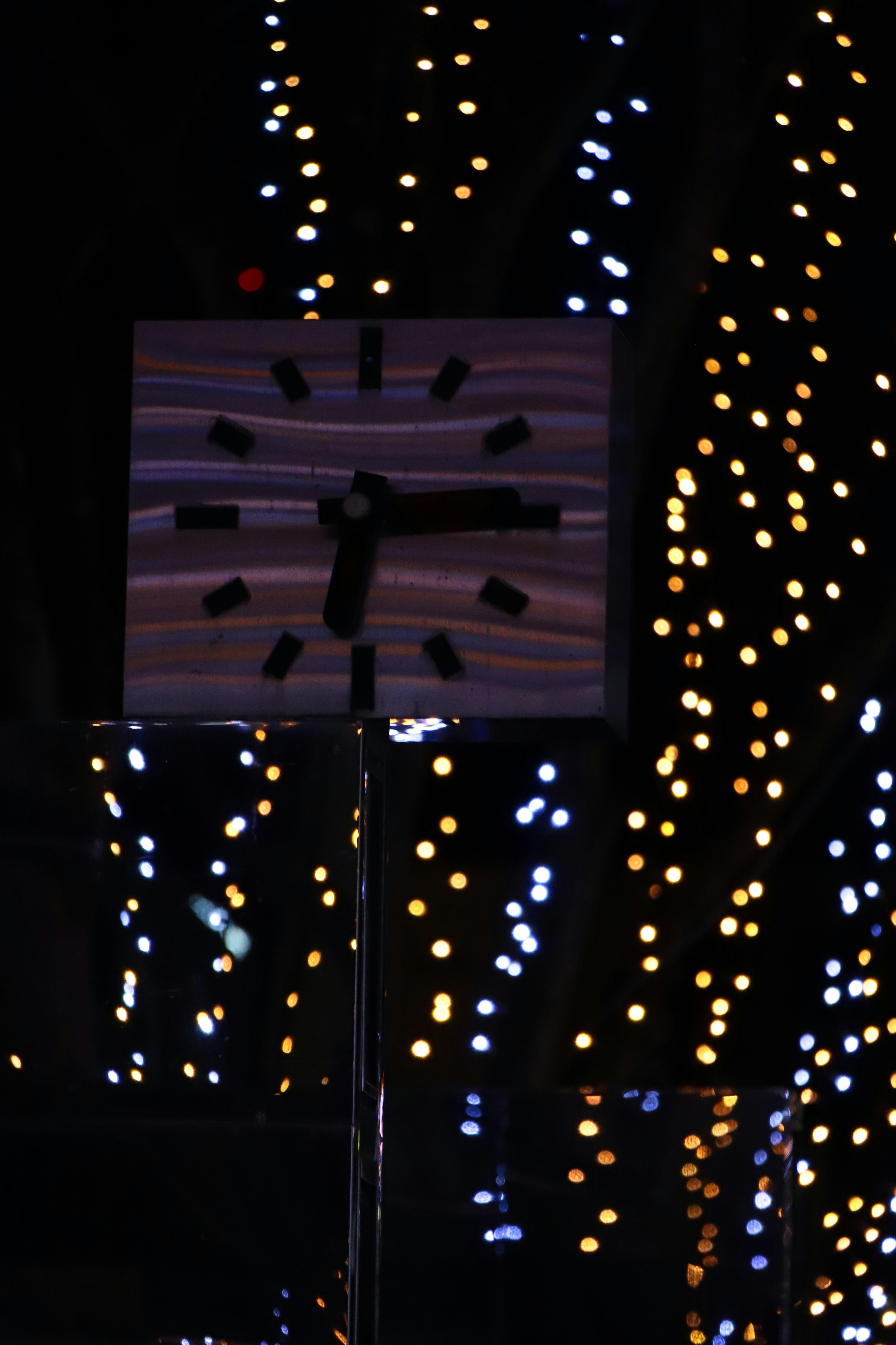 Reloj contra un fondo oscuro con luces brillantes