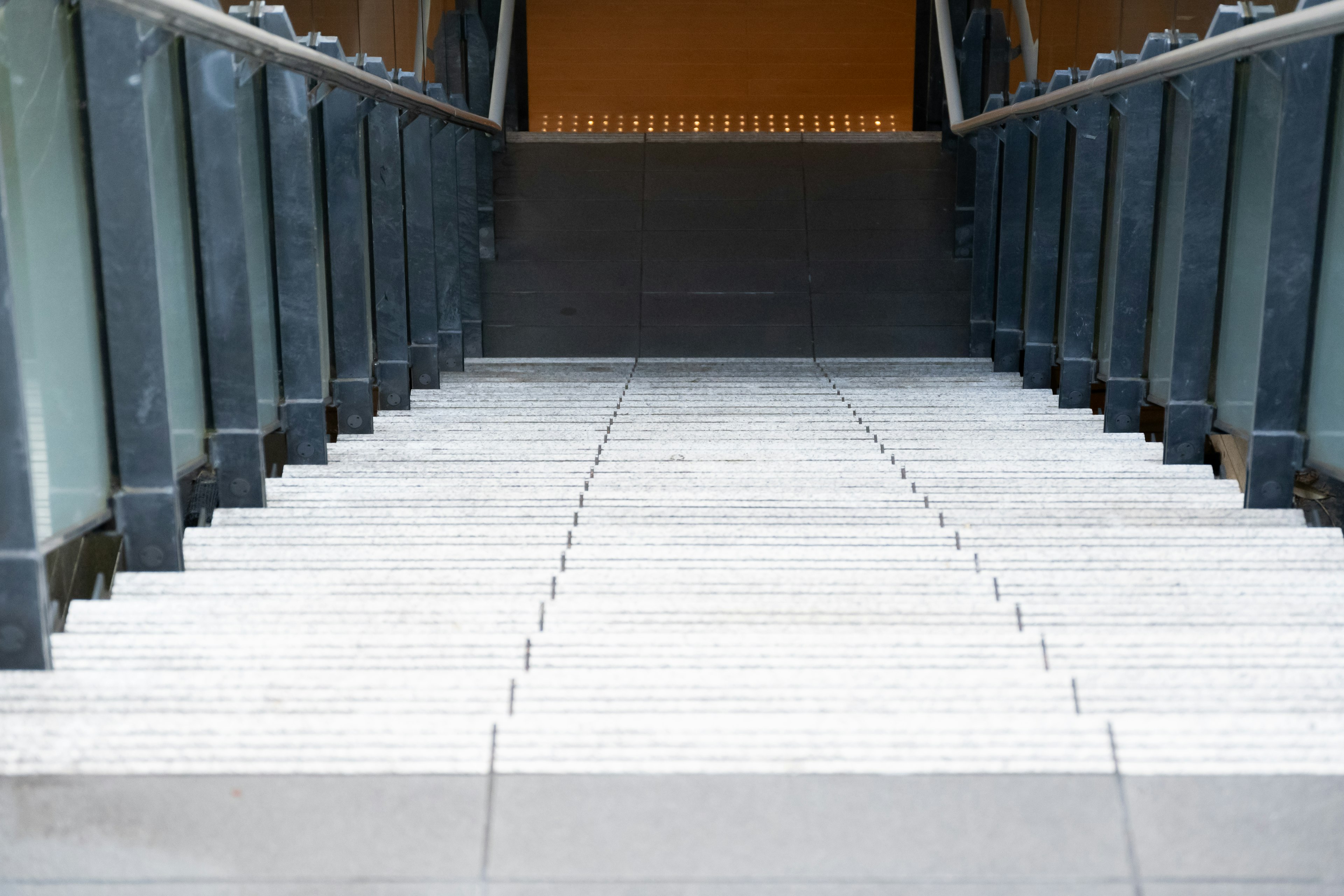 Blick von oben auf eine Treppe mit weißen Platten und Metallgeländern