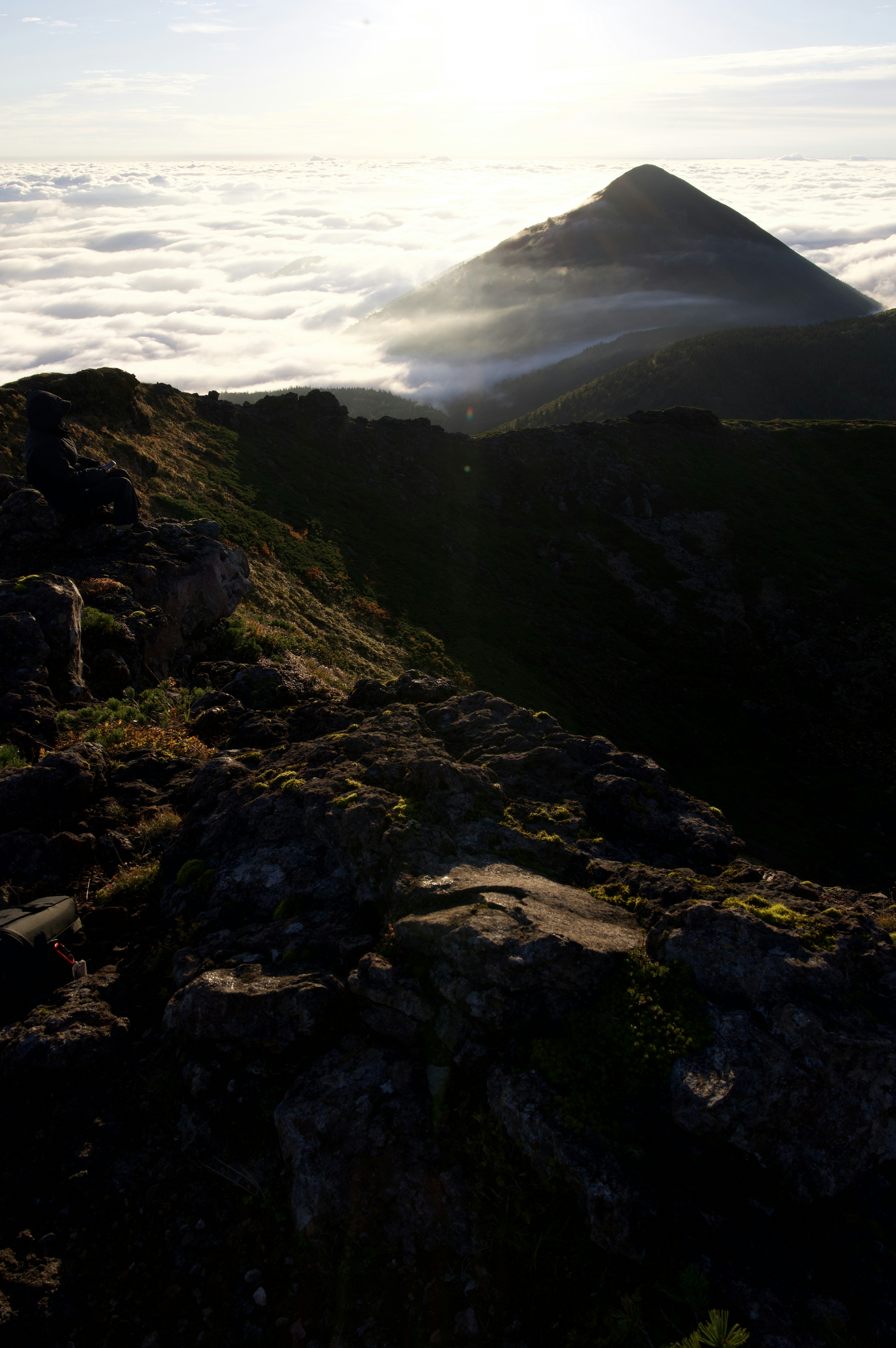 Sommet de montagne émergeant des nuages avec un premier plan rocheux