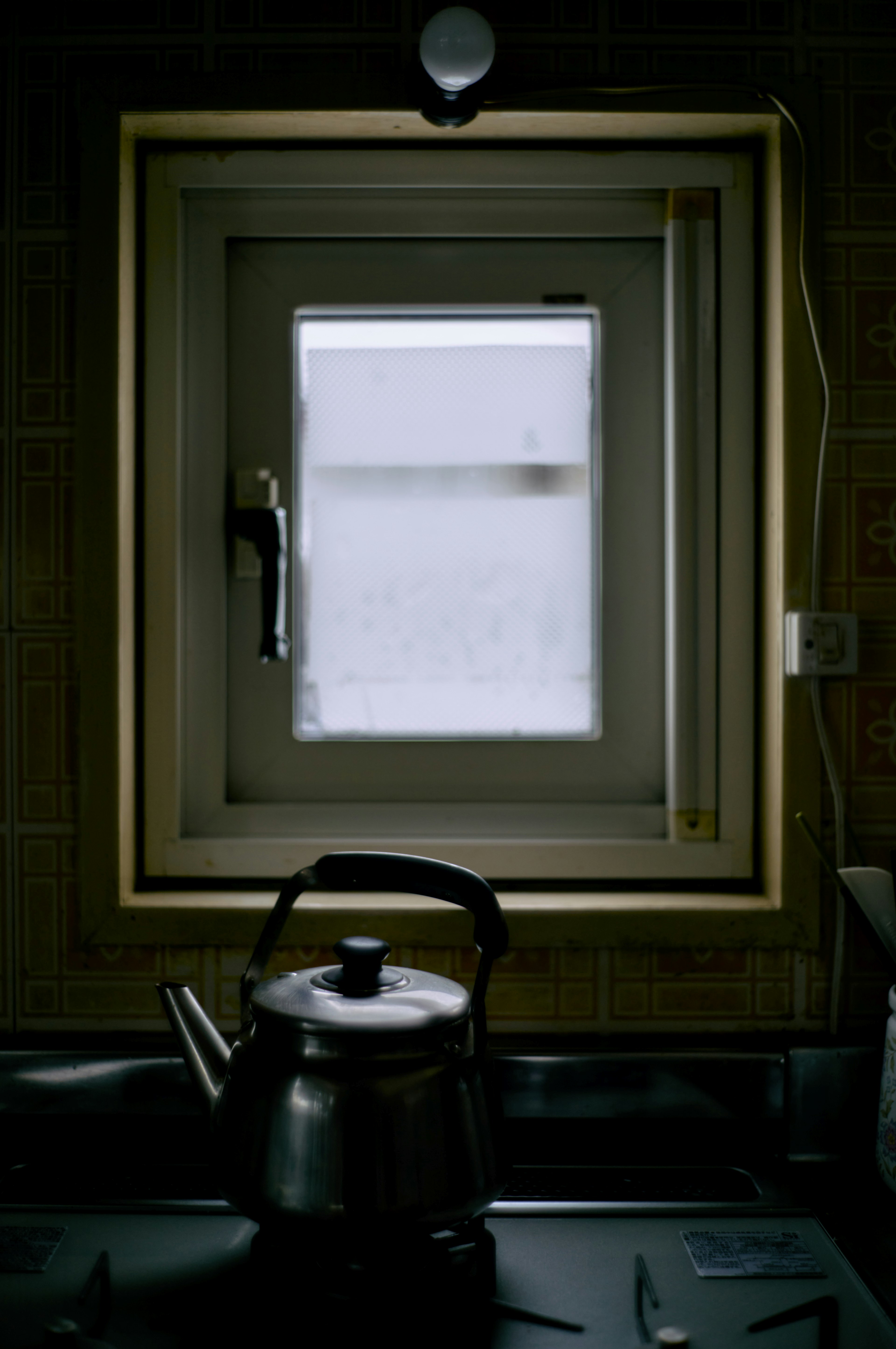 Küchenfenster mit einem Wasserkocher auf dem Herd Fenster mit weißem Vorhang Wasserkocher ist metallisch und einfach