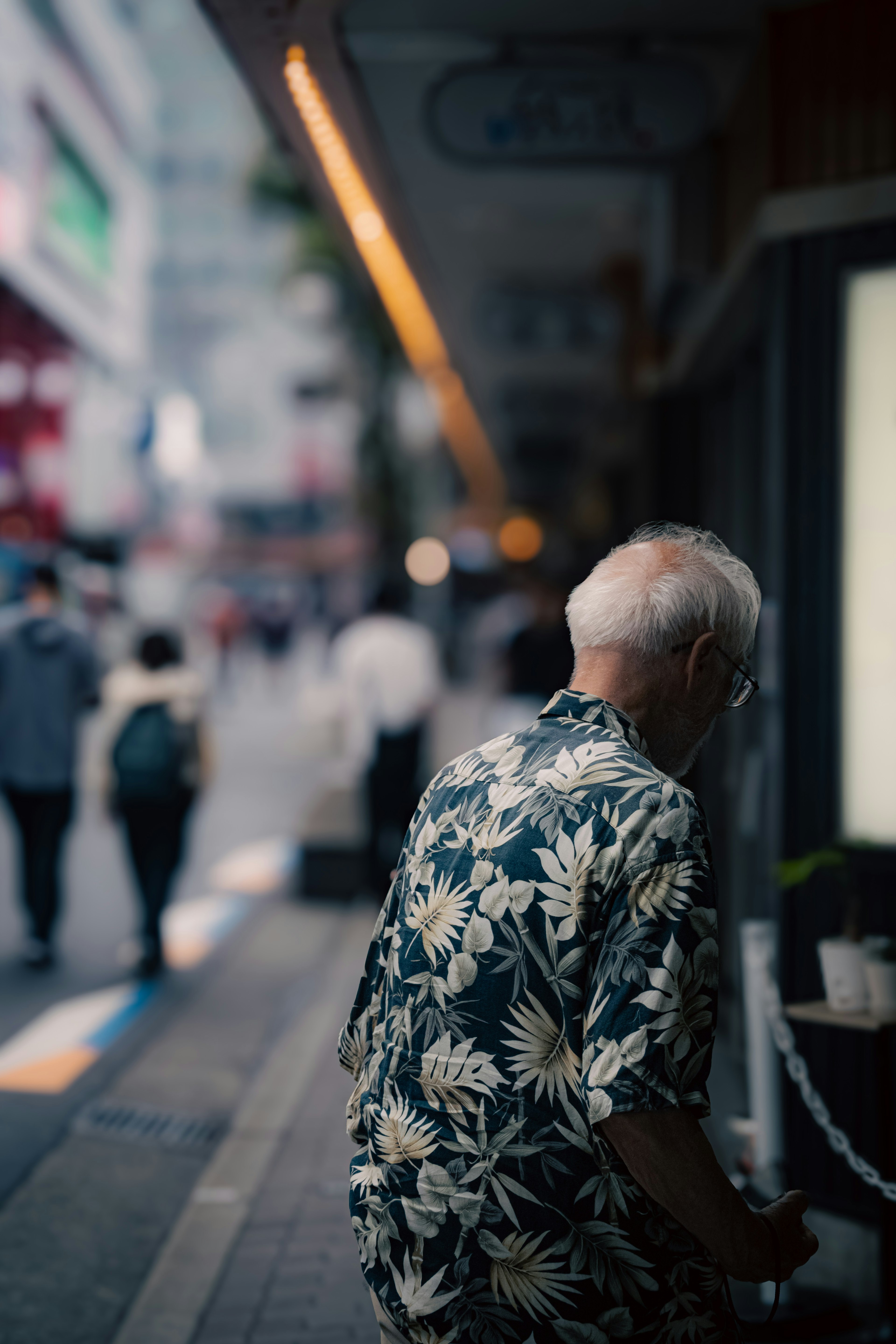 街の通りを歩く高齢者の後ろ姿 花柄のシャツを着ている