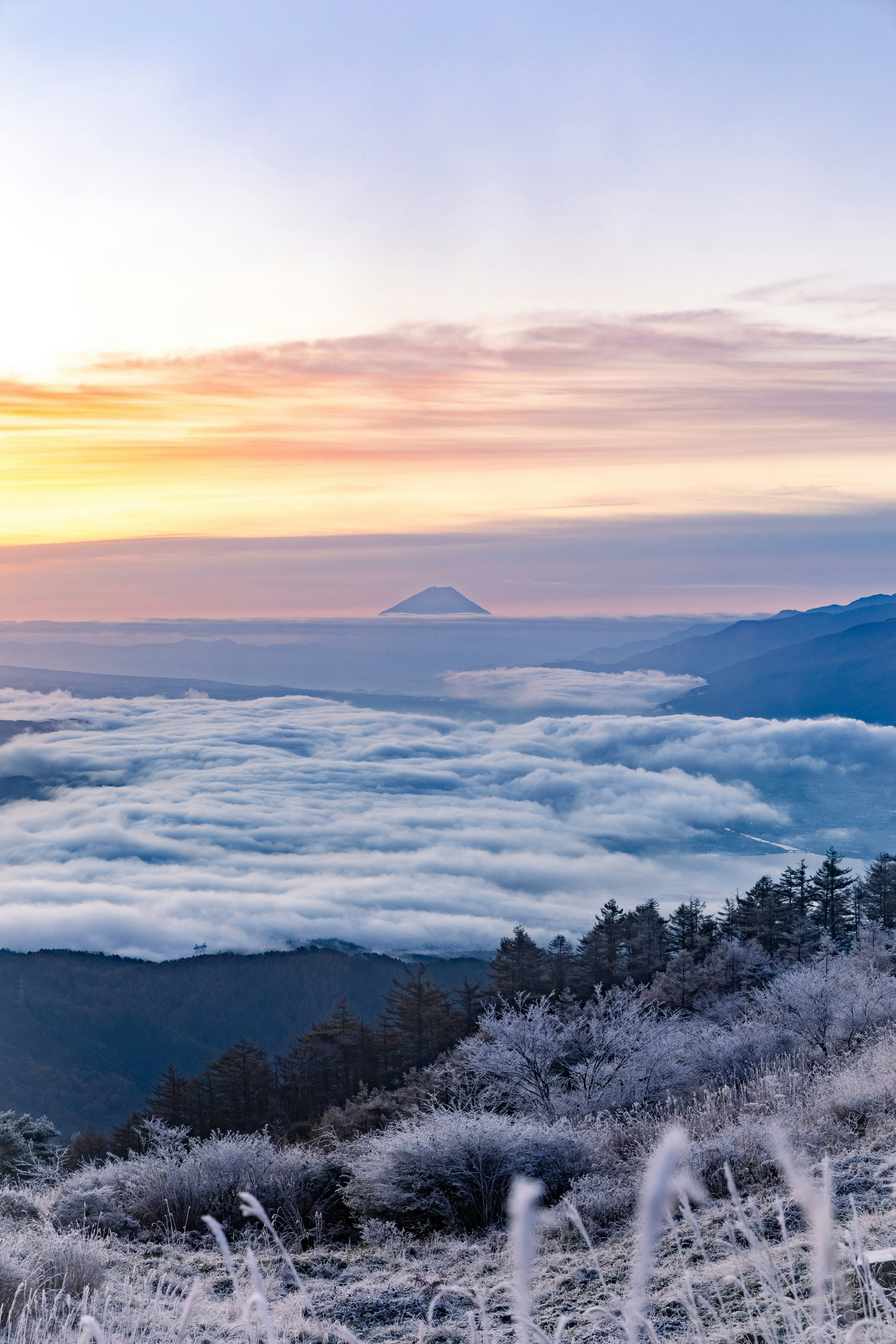 Paisaje invernal con niebla cubriendo montañas y amanecer