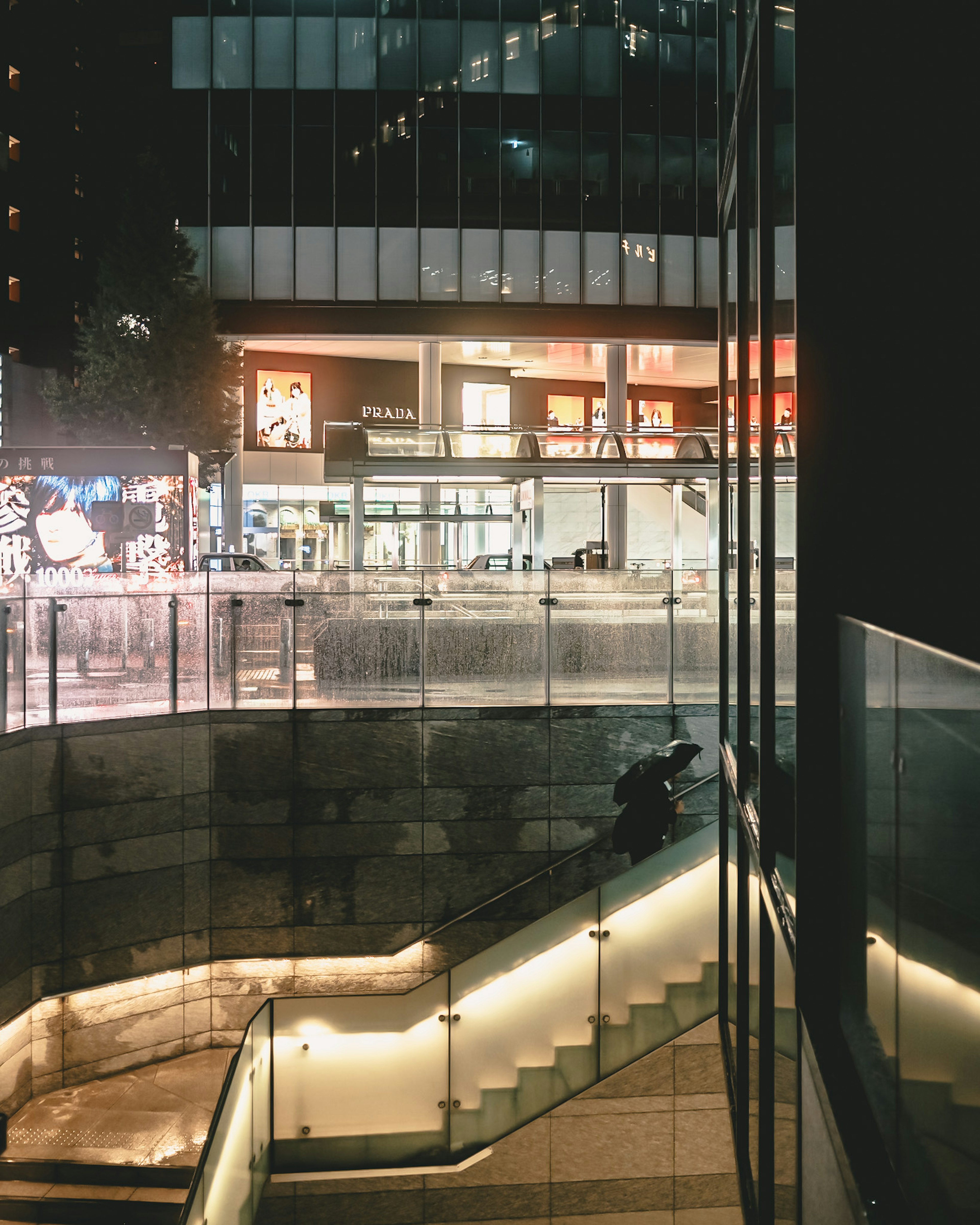 Urban nighttime scene featuring a modern building and illuminated staircase