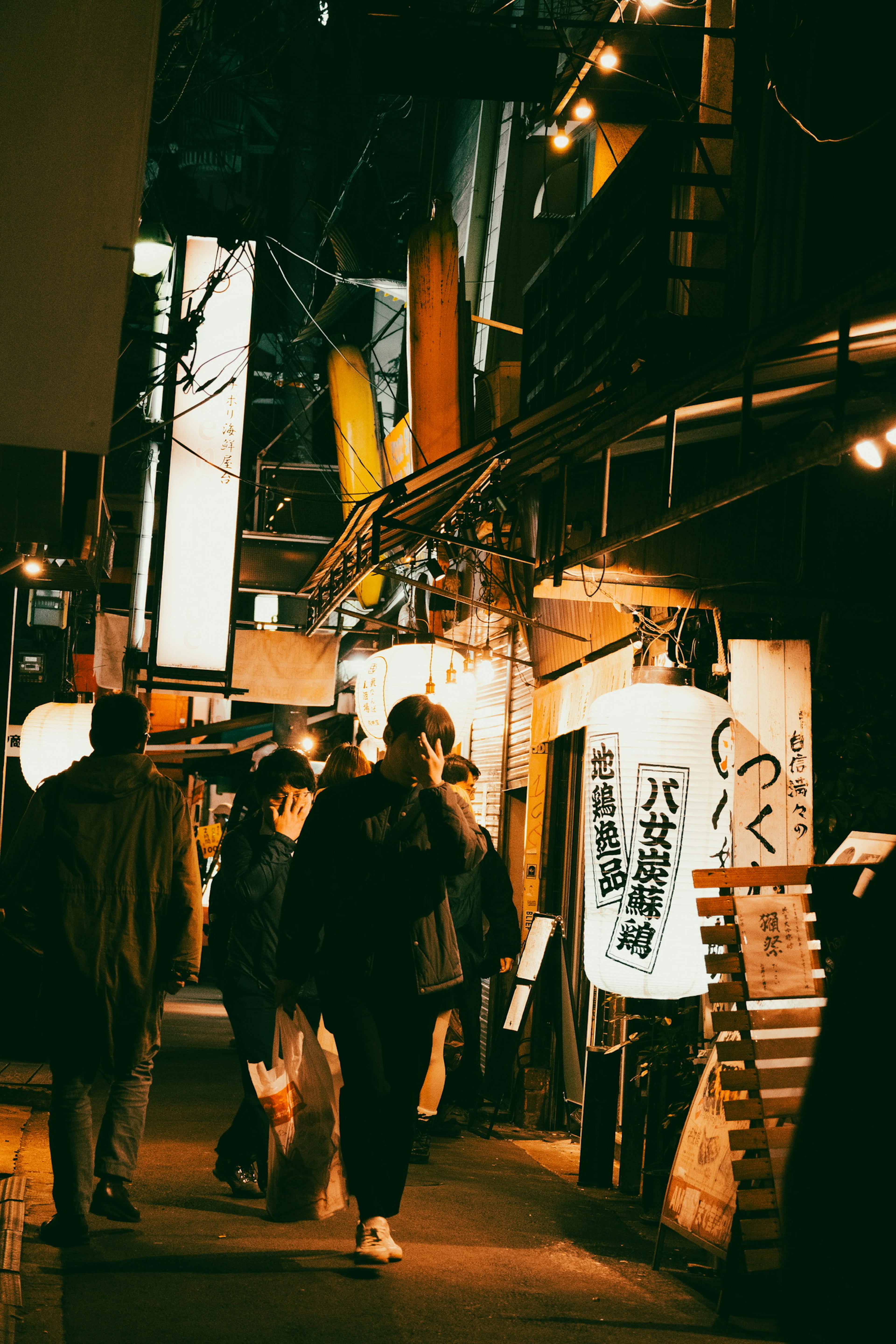 People walking in a nighttime street with illuminated signs