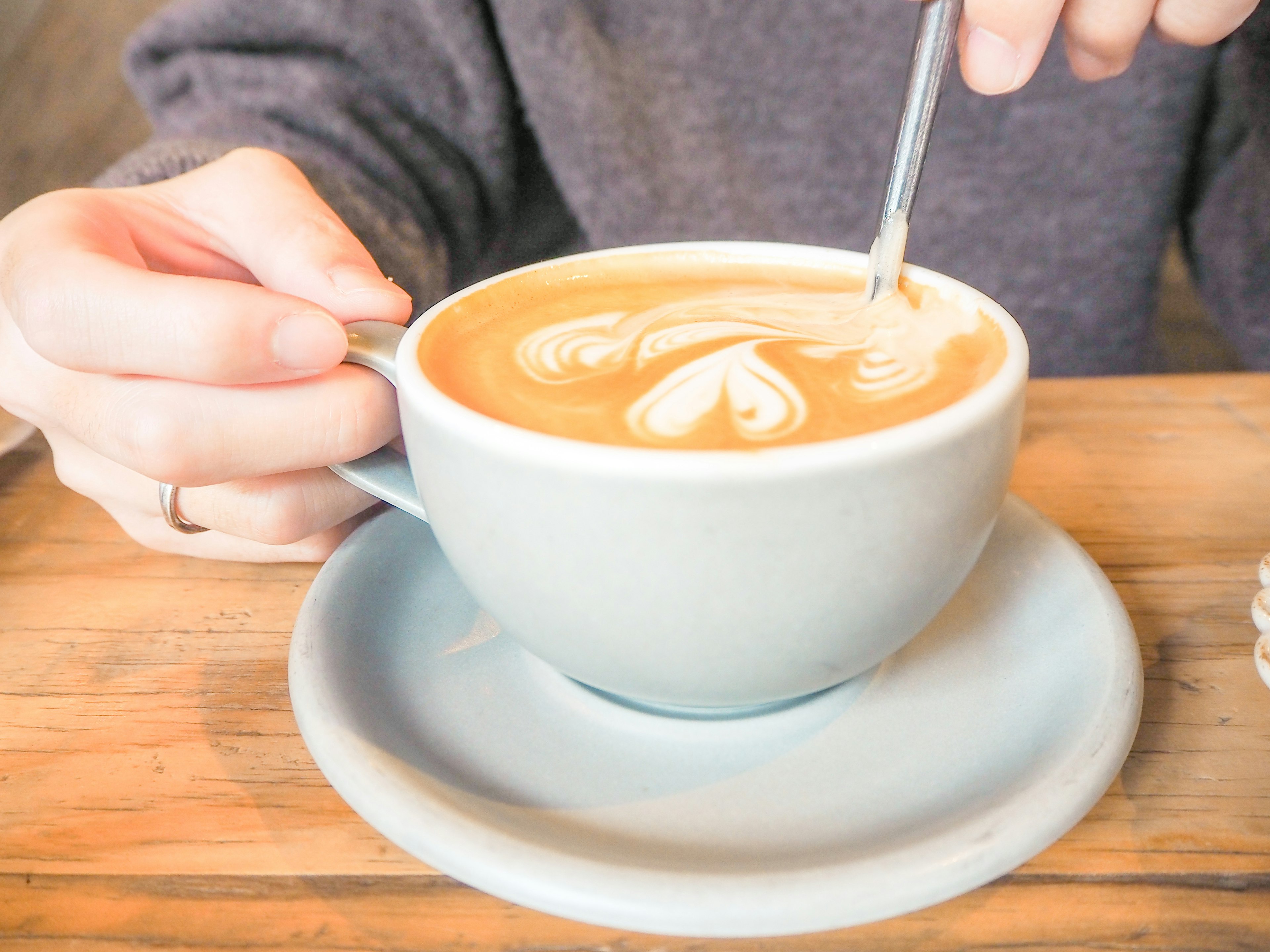 Eine Person hält eine Tasse mit schöner Latte-Art