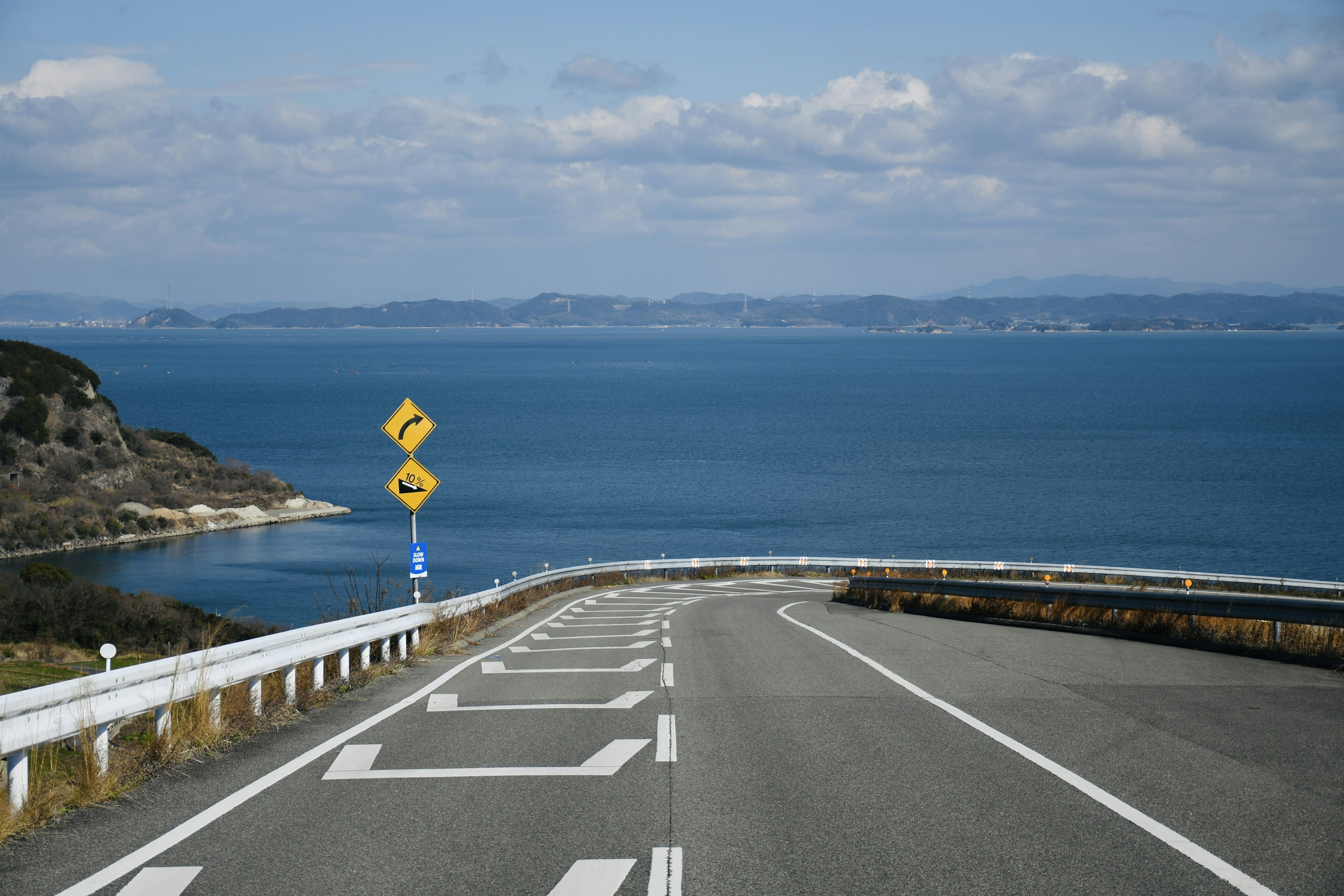 Carretera curva junto al mar con cielo azul