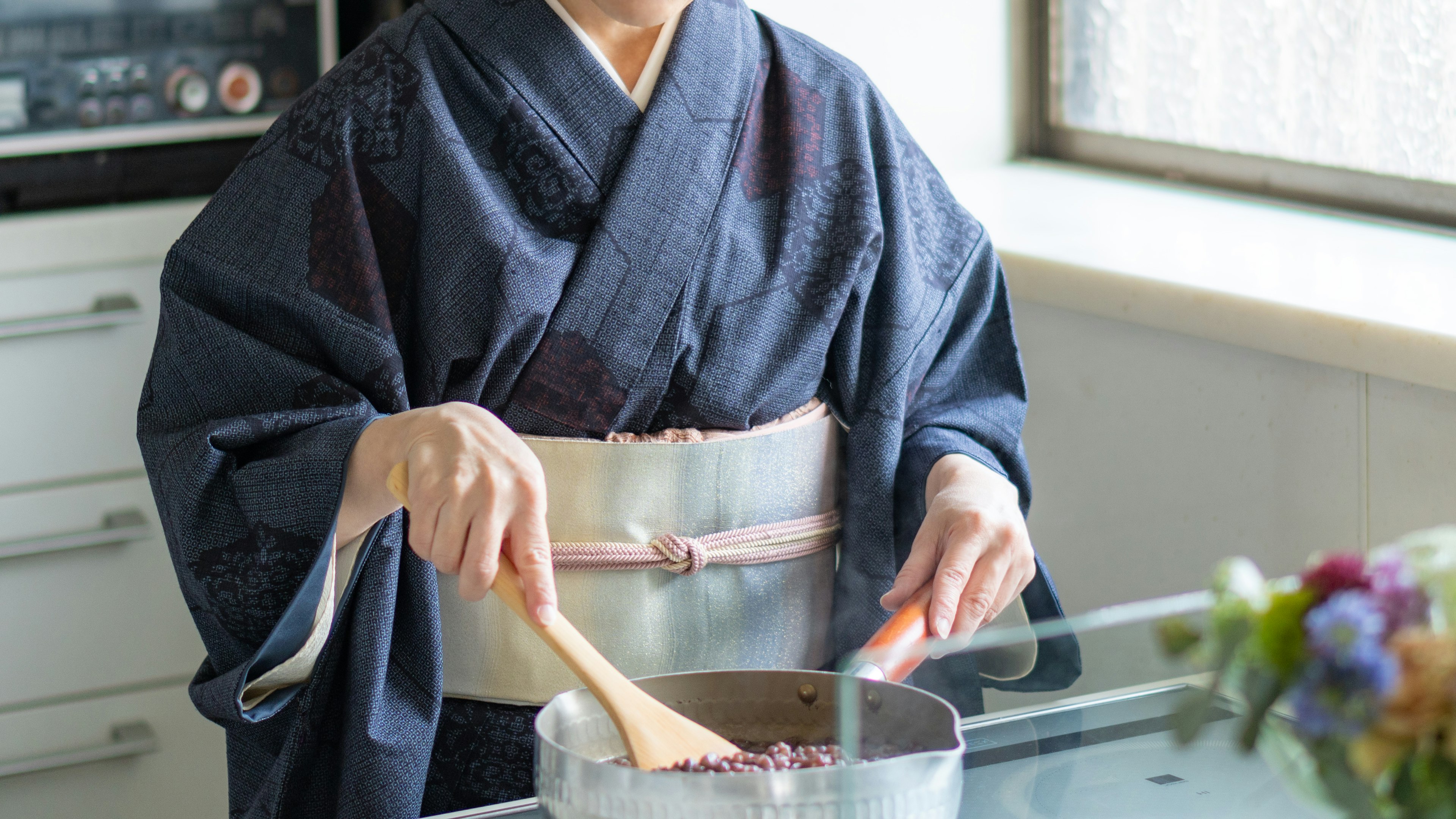 Woman in kimono stirring pot in a modern kitchen