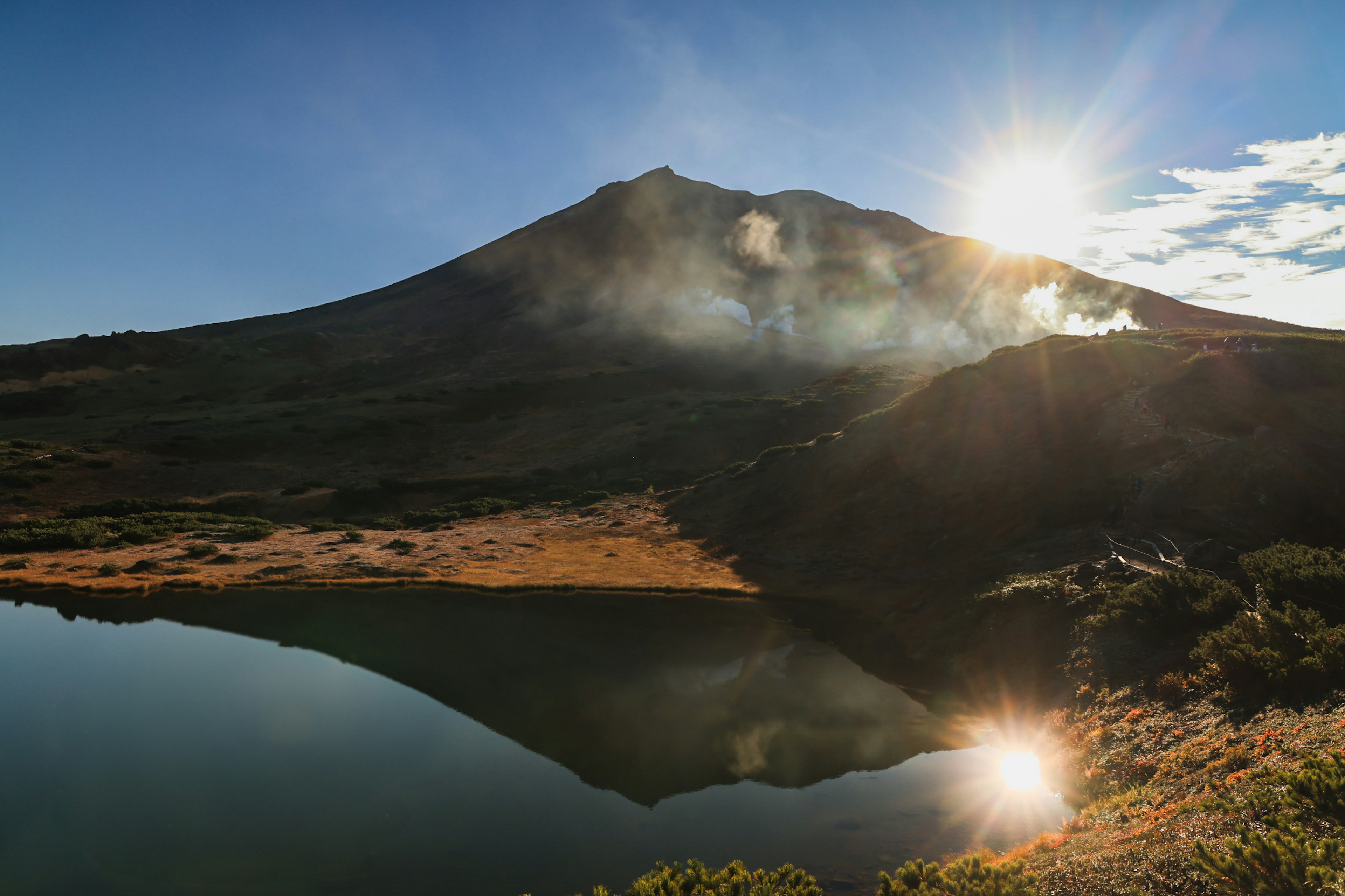 美しい火山と穏やかな湖の風景太陽が山の上に輝いている