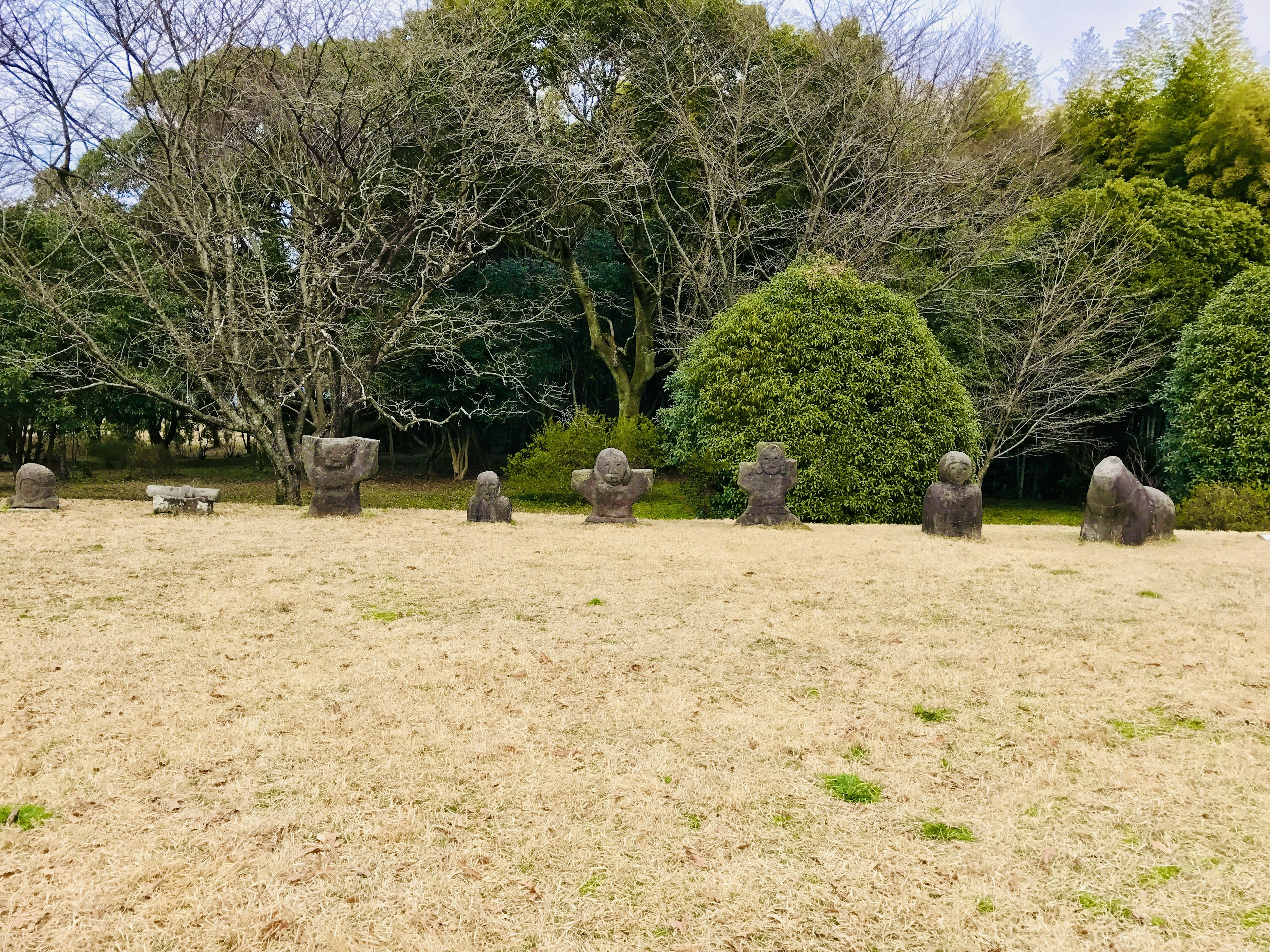 Estatuas de piedra dispuestas en un parque con árboles verdes