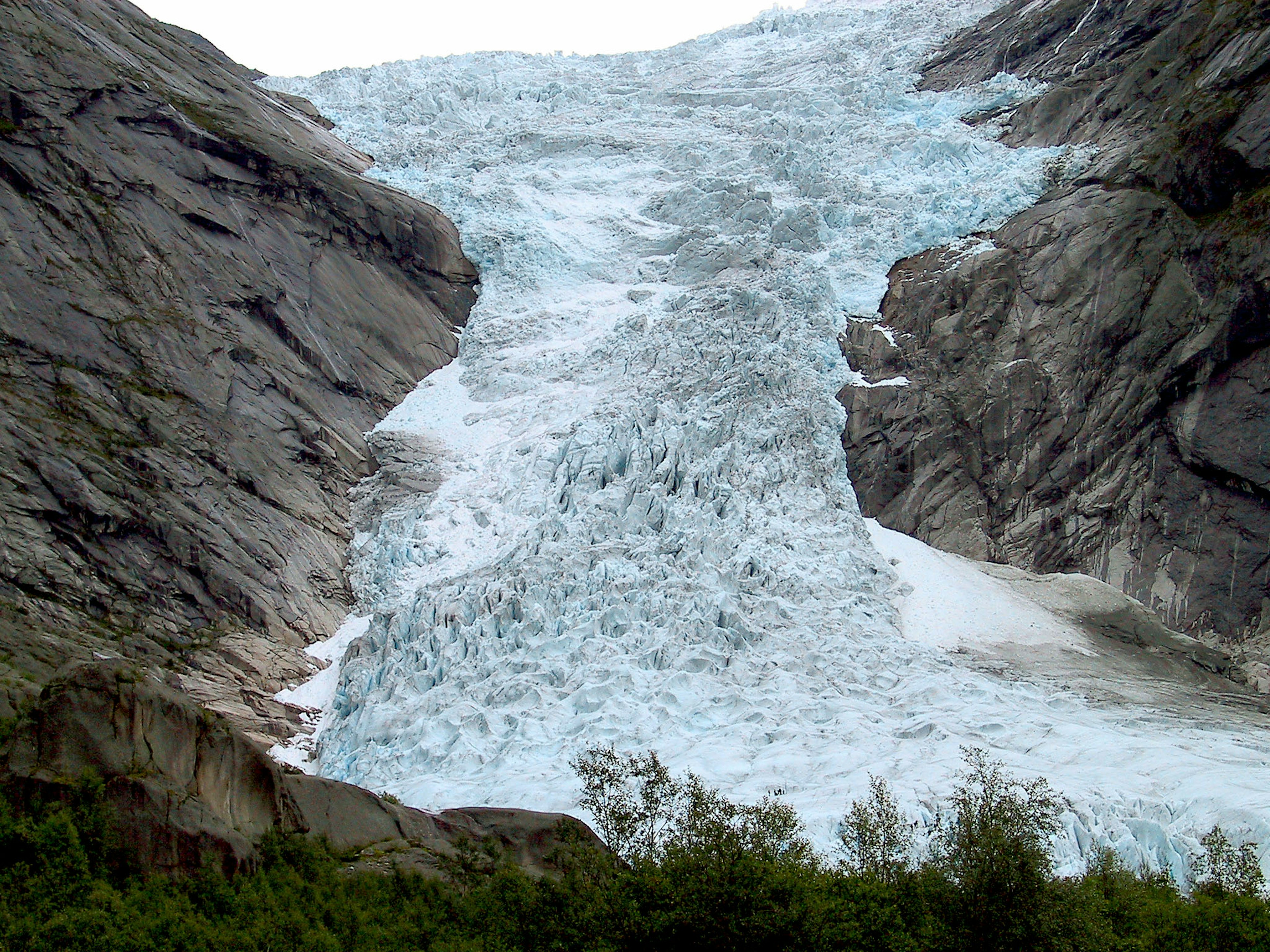 Glacier flowing between rocky cliffs in a natural landscape