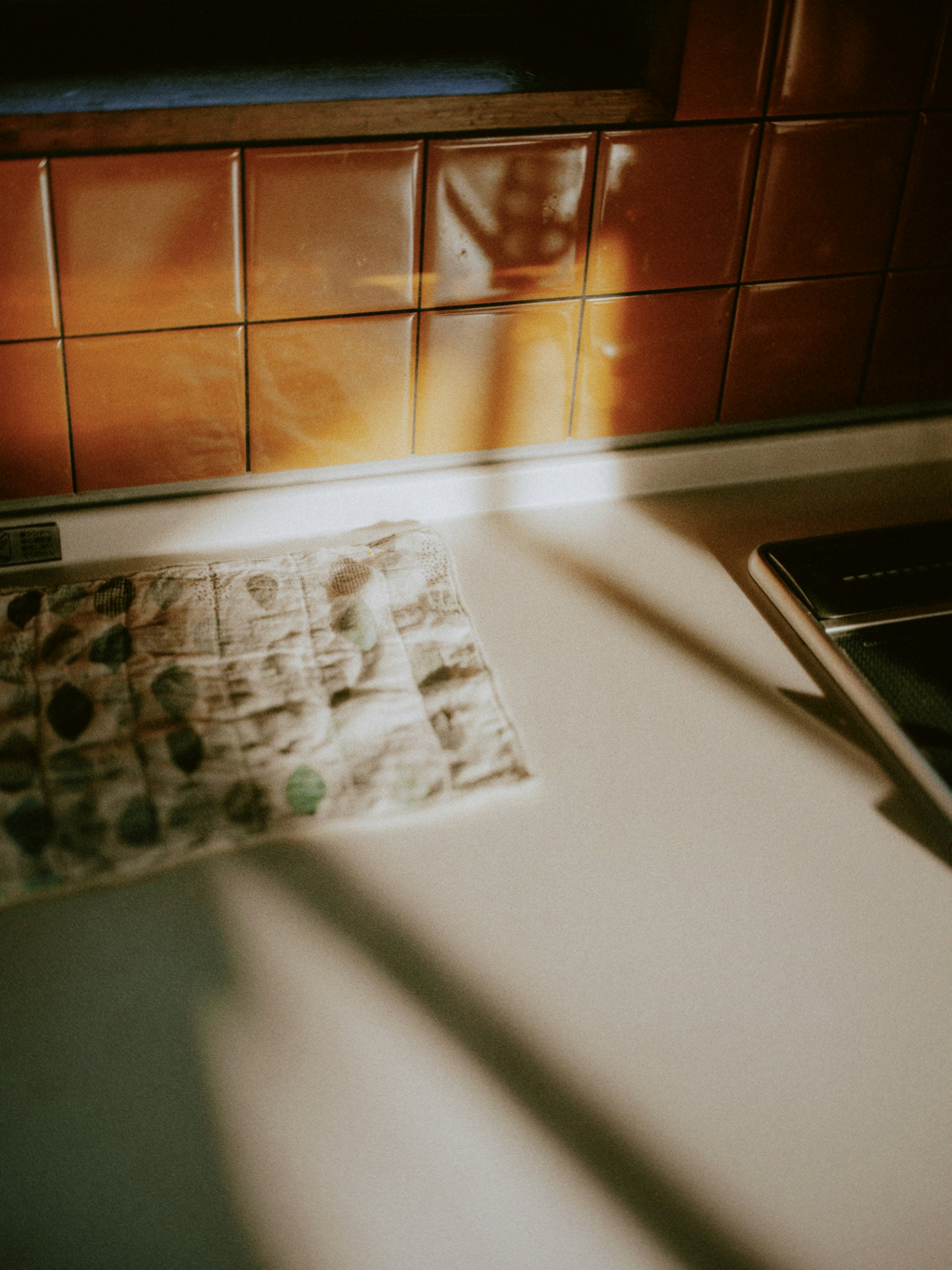 A kitchen counter with a newspaper and beautiful light casting shadows