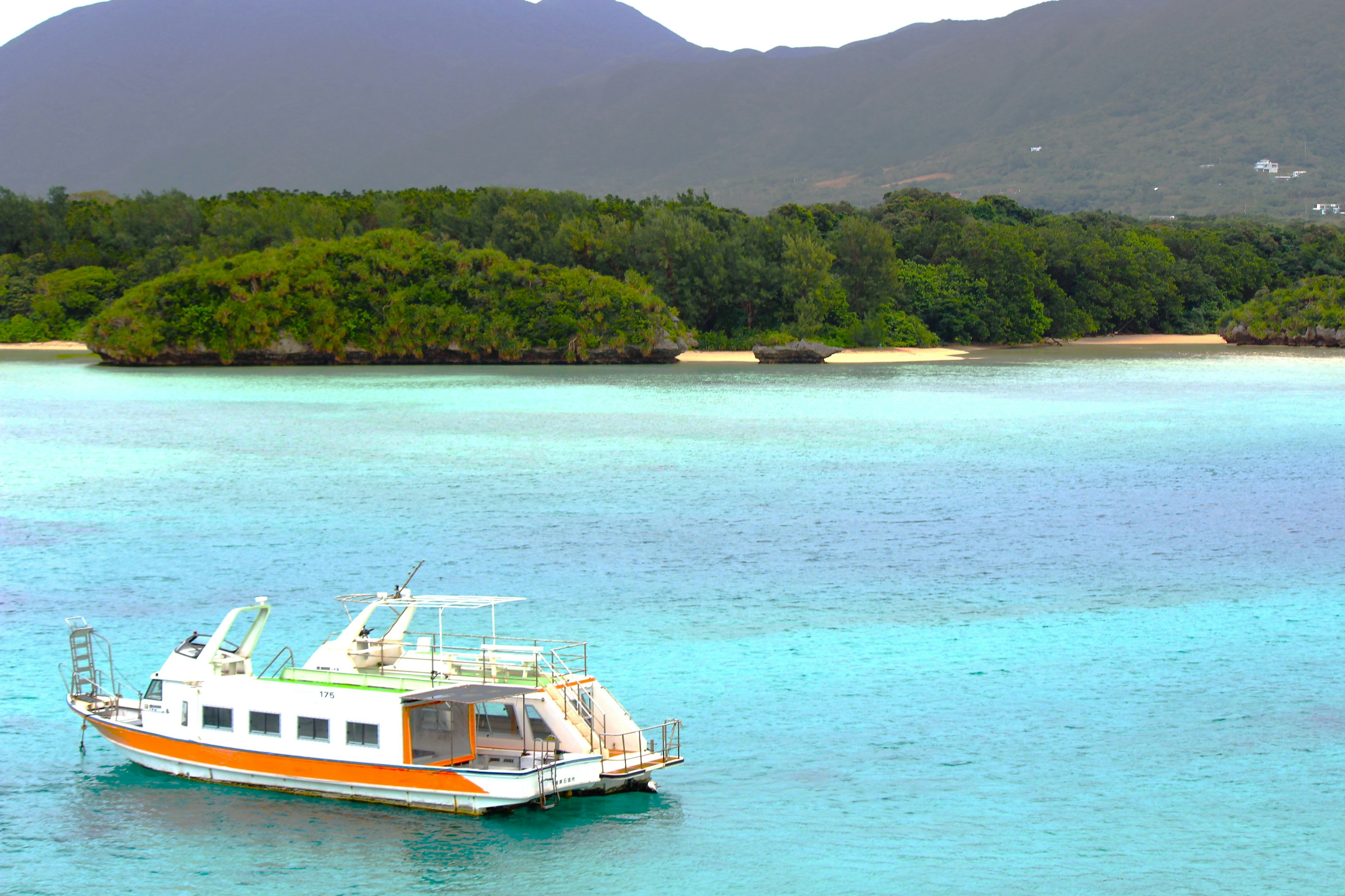 Un bote flotando en un hermoso mar azul con islas verdes