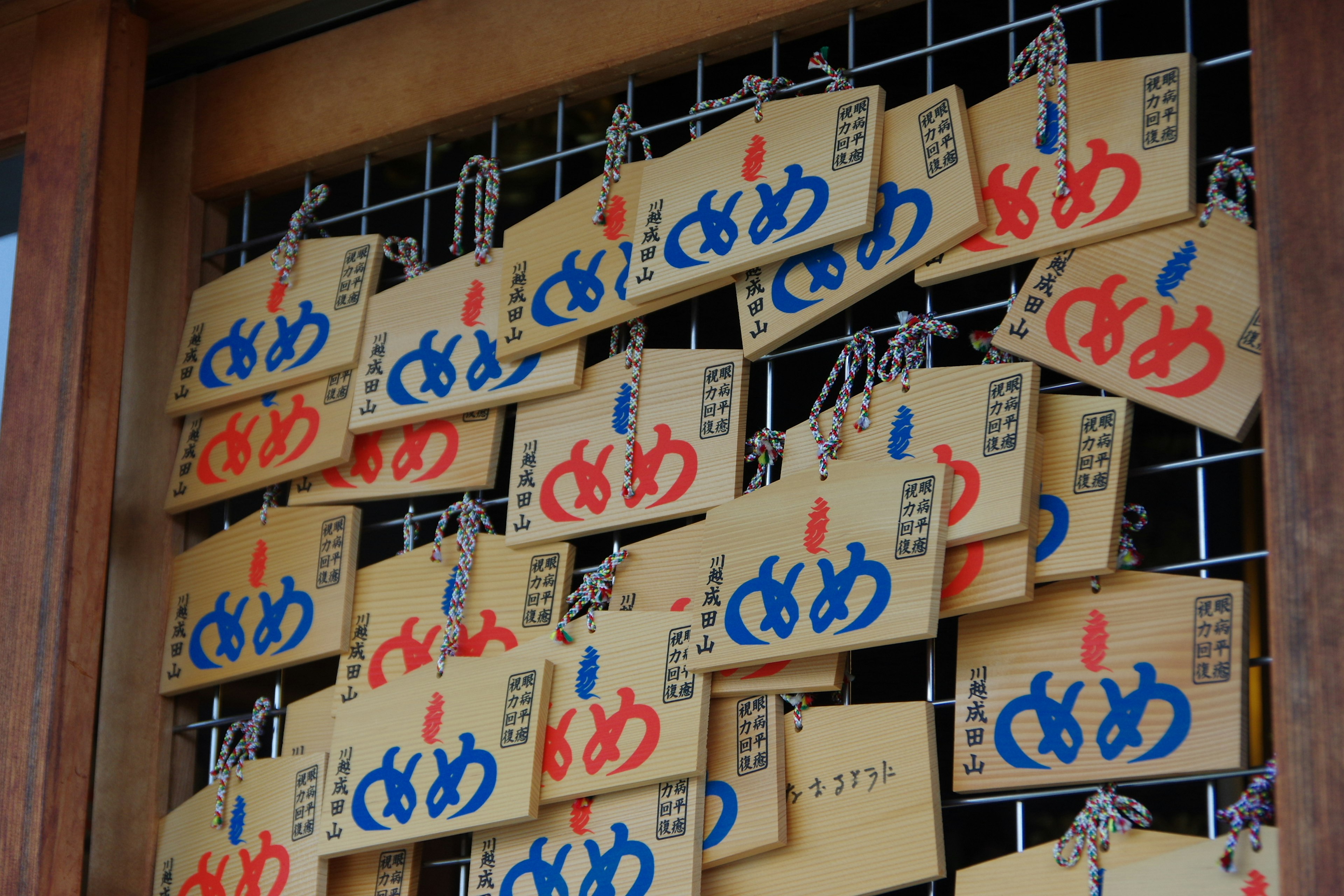 Wooden plaques with blue and red inscriptions displaying wishes or messages