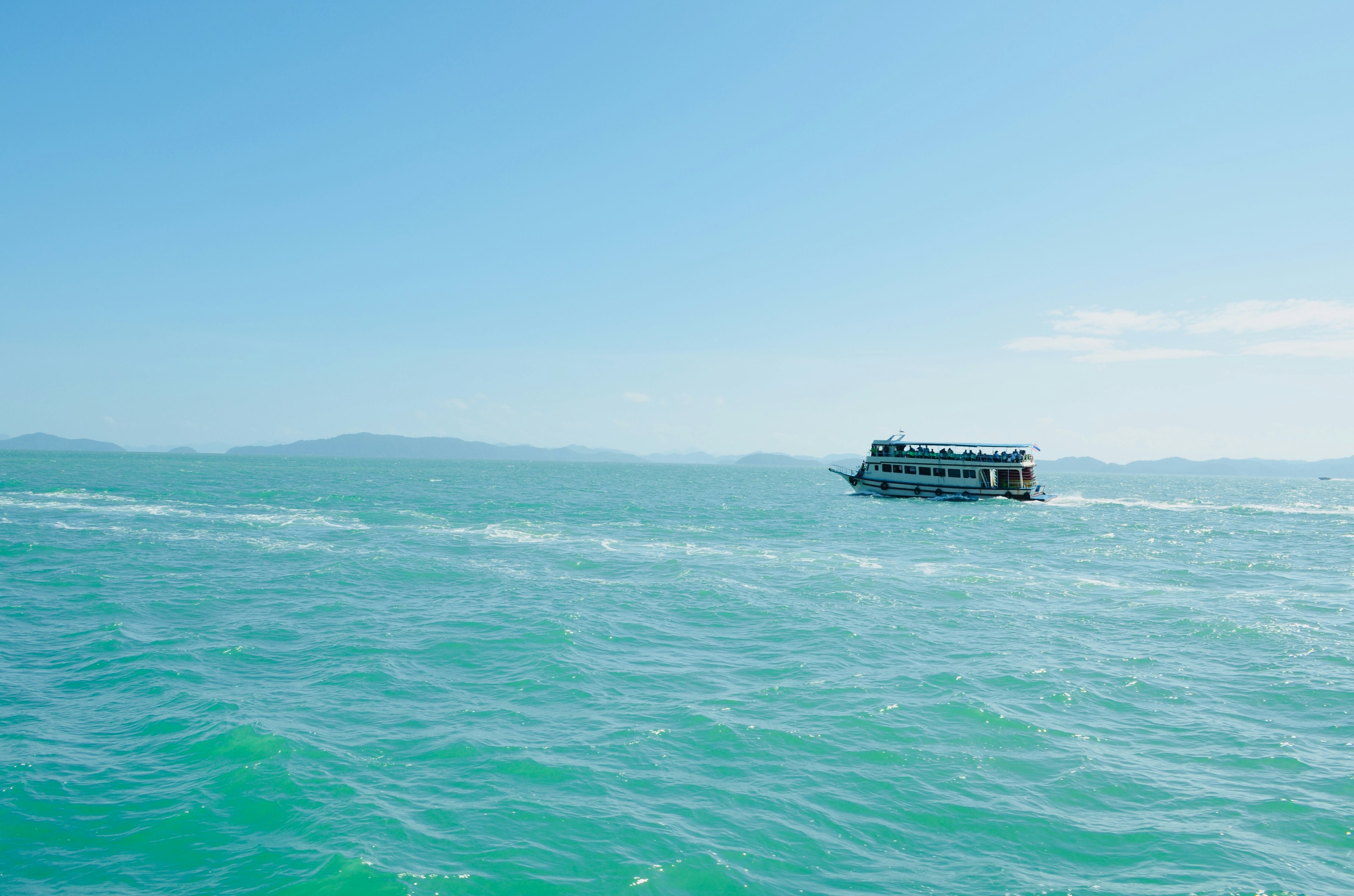 Sebuah perahu bergerak di laut biru di bawah langit cerah