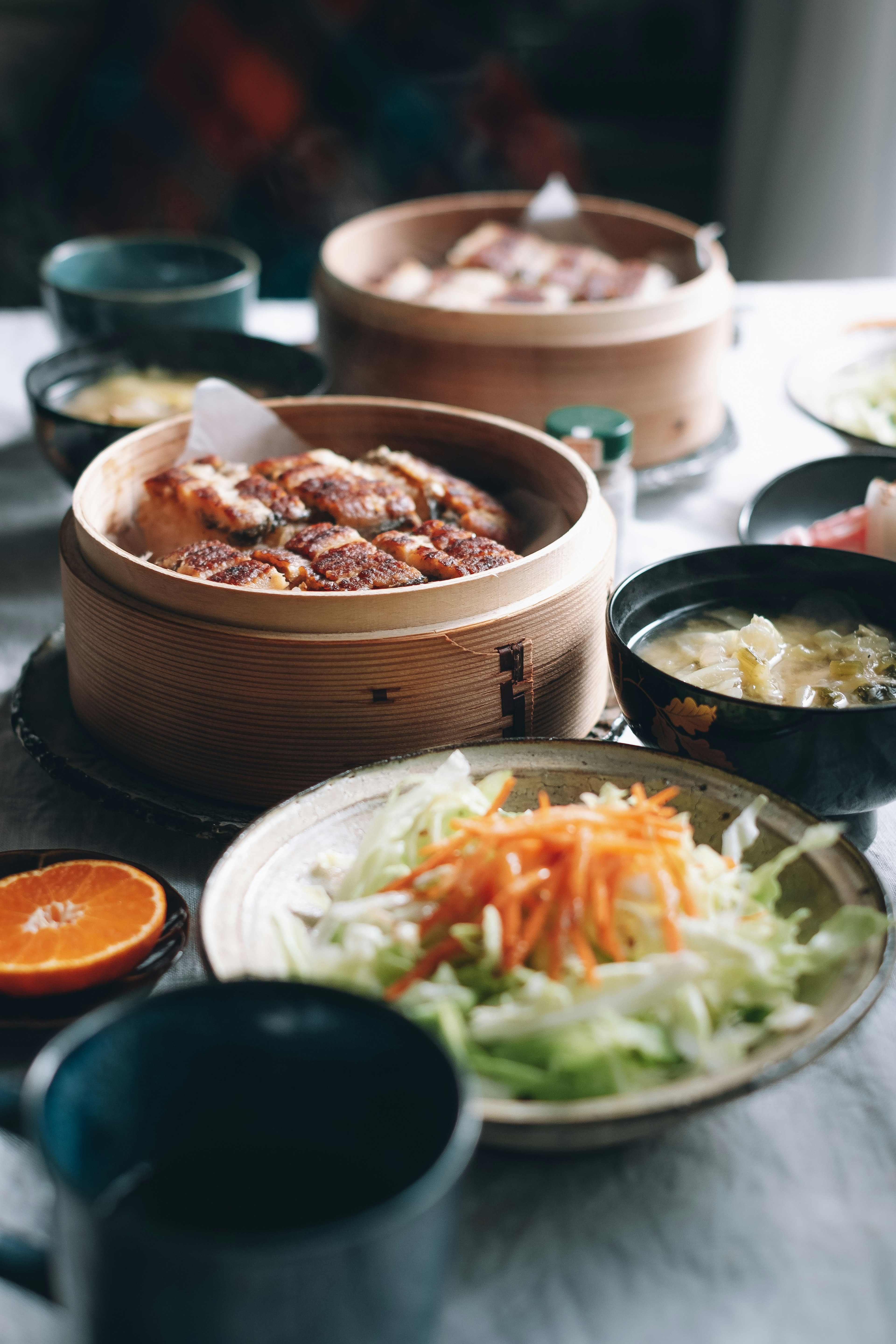 Table set with bamboo steamer dishes and fresh salad