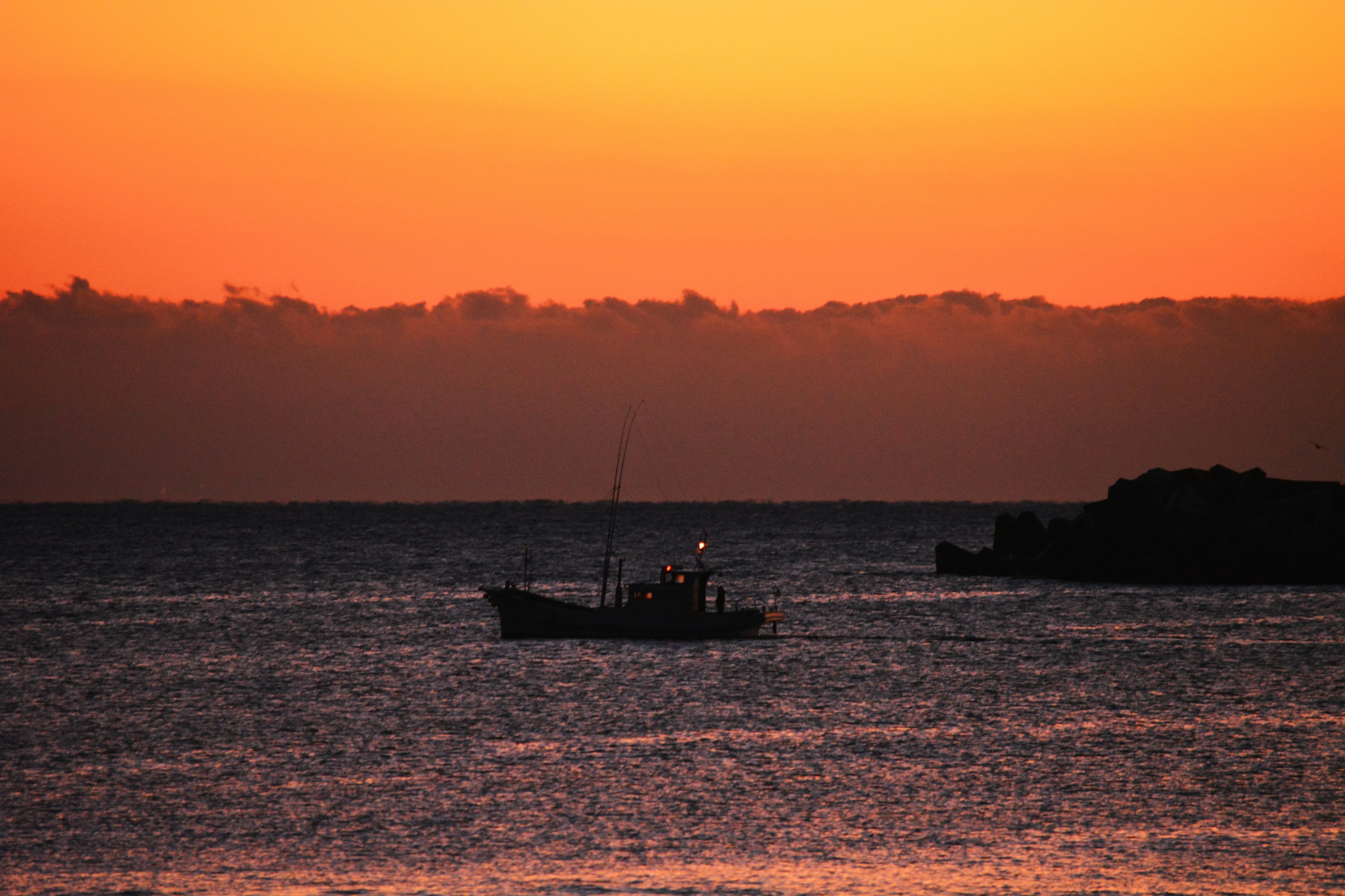 夕焼けの海に浮かぶ漁船と穏やかな波