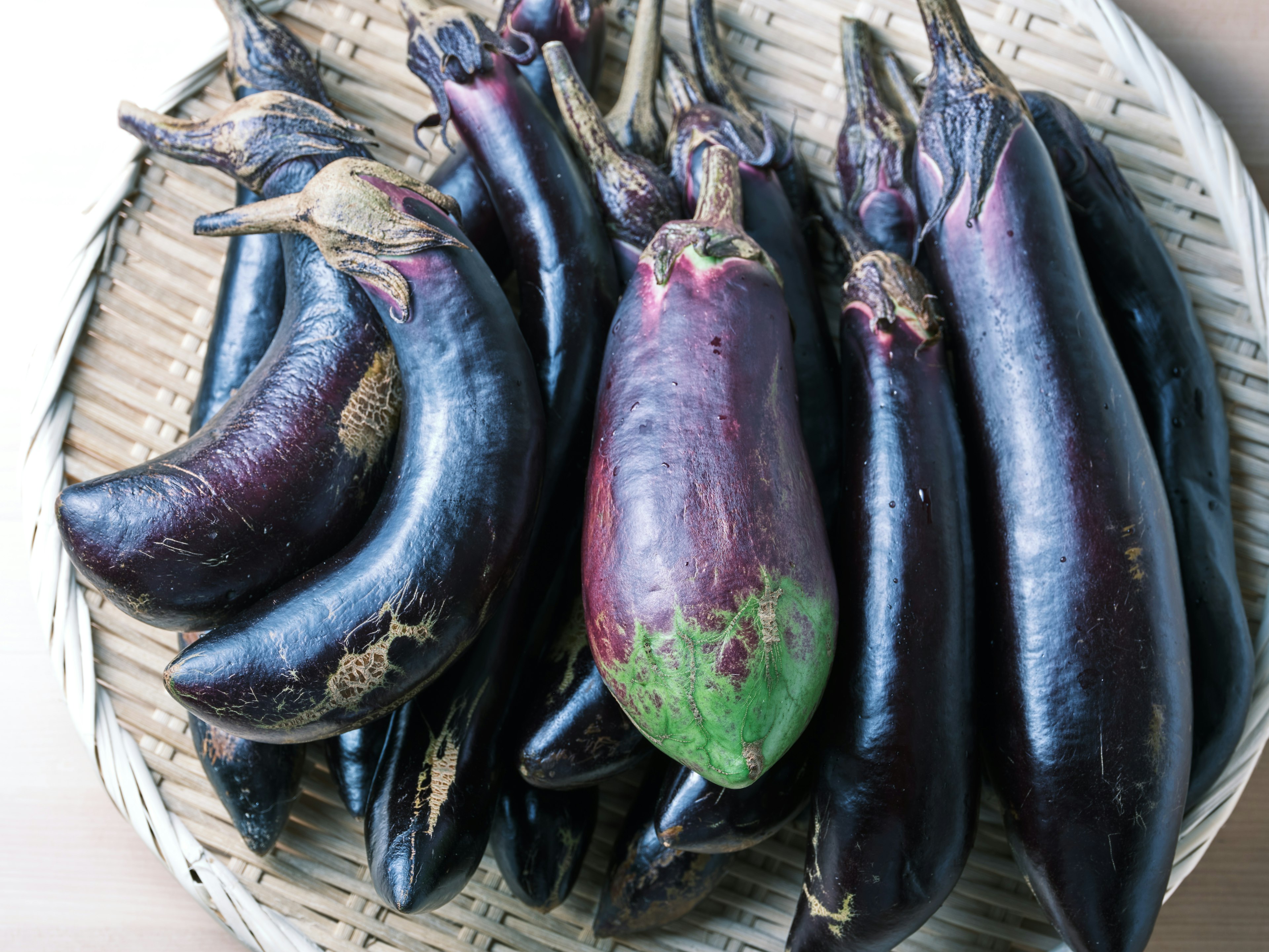 A basket filled with various purple eggplants