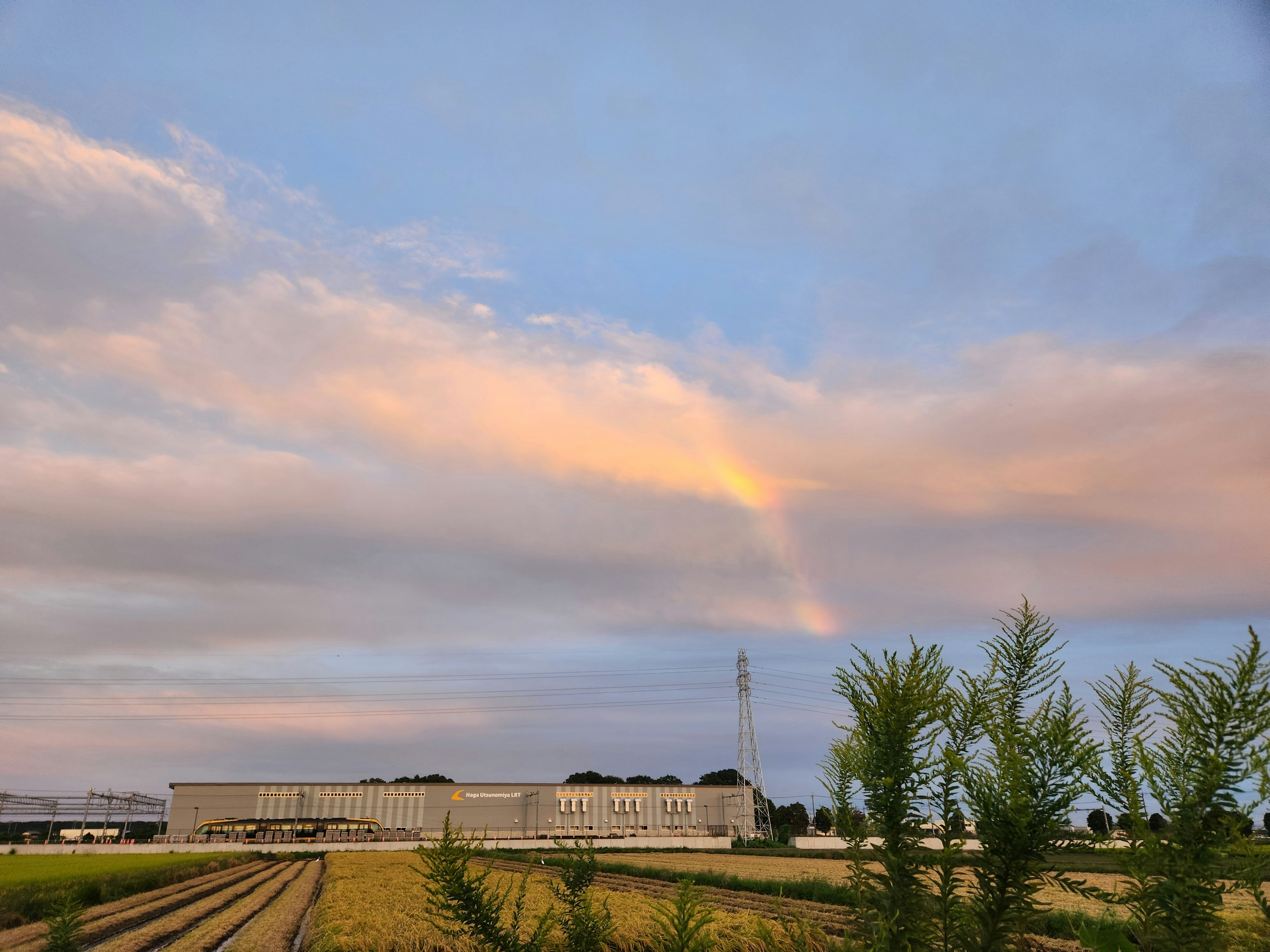 青空と雲の間にかかる虹と田園風景