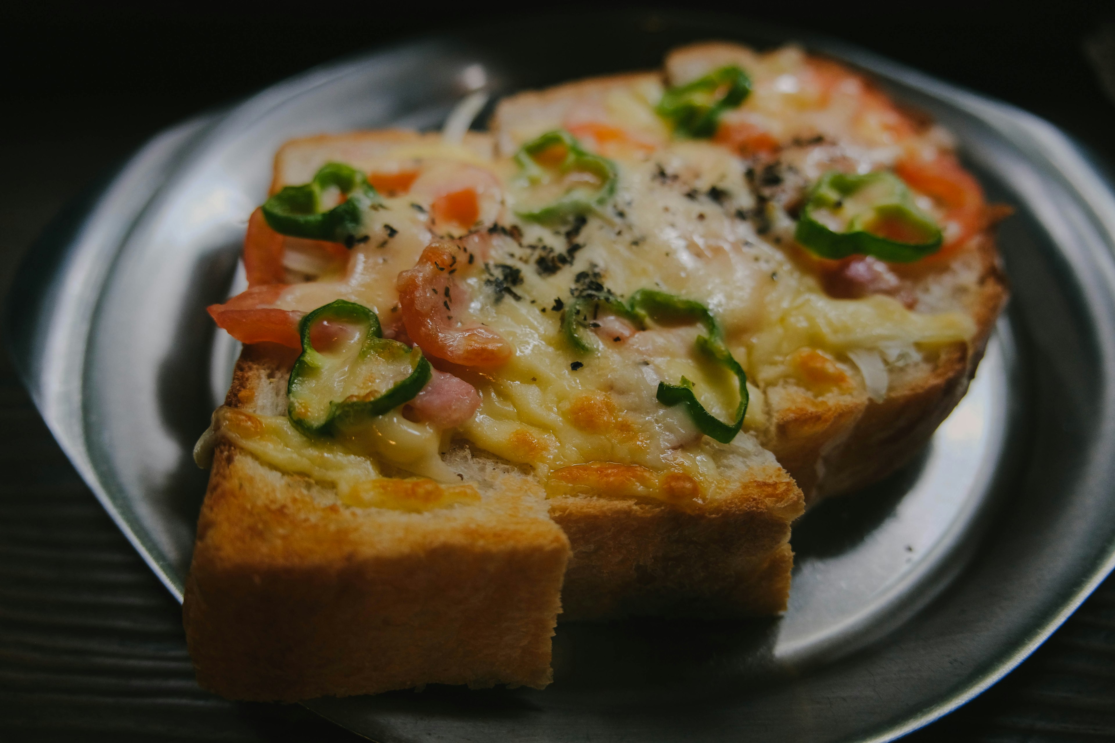 Toasted bread topped with tomatoes, ham, and jalapeños