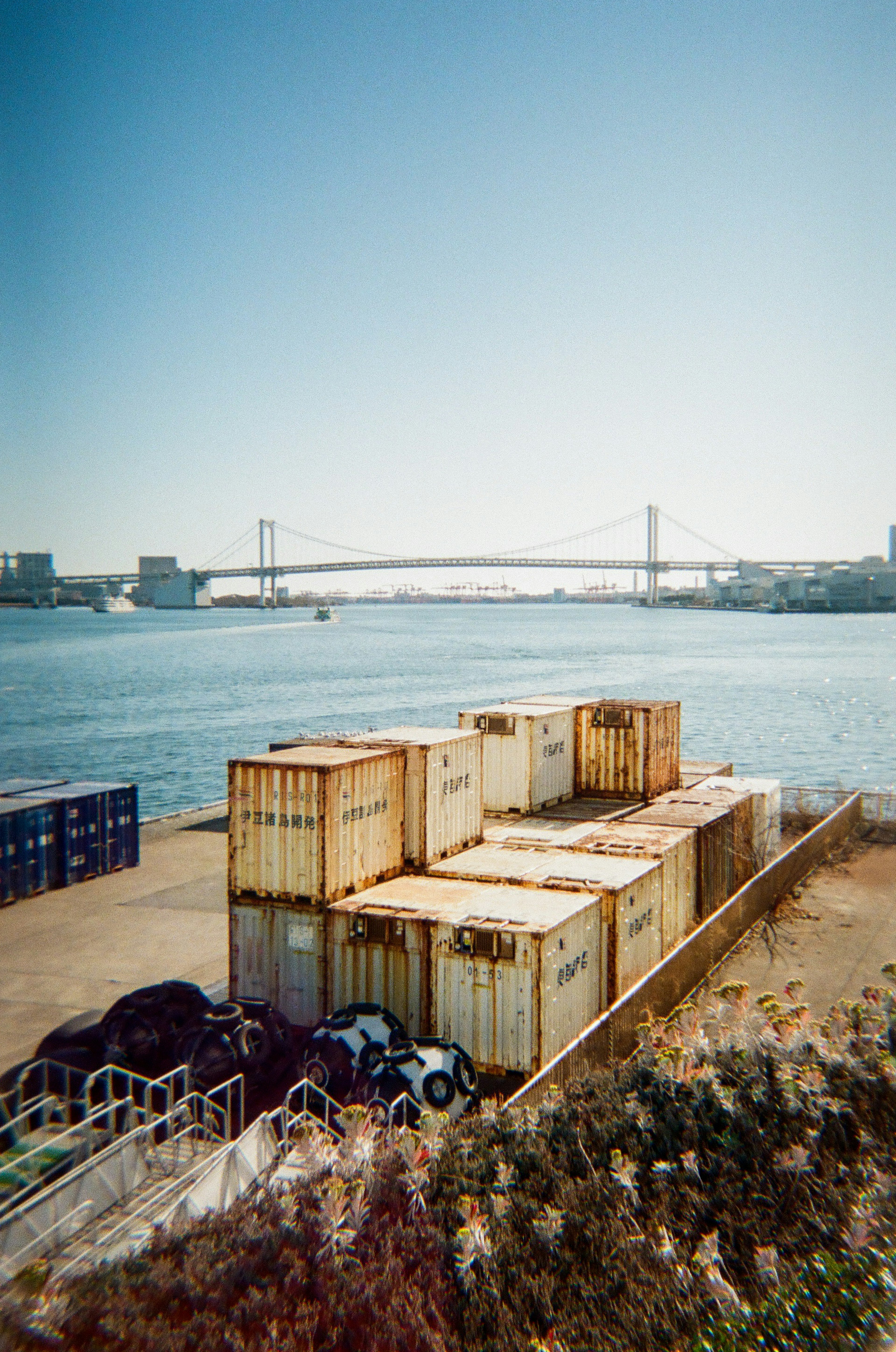 Containers by the waterfront with a bridge in the background