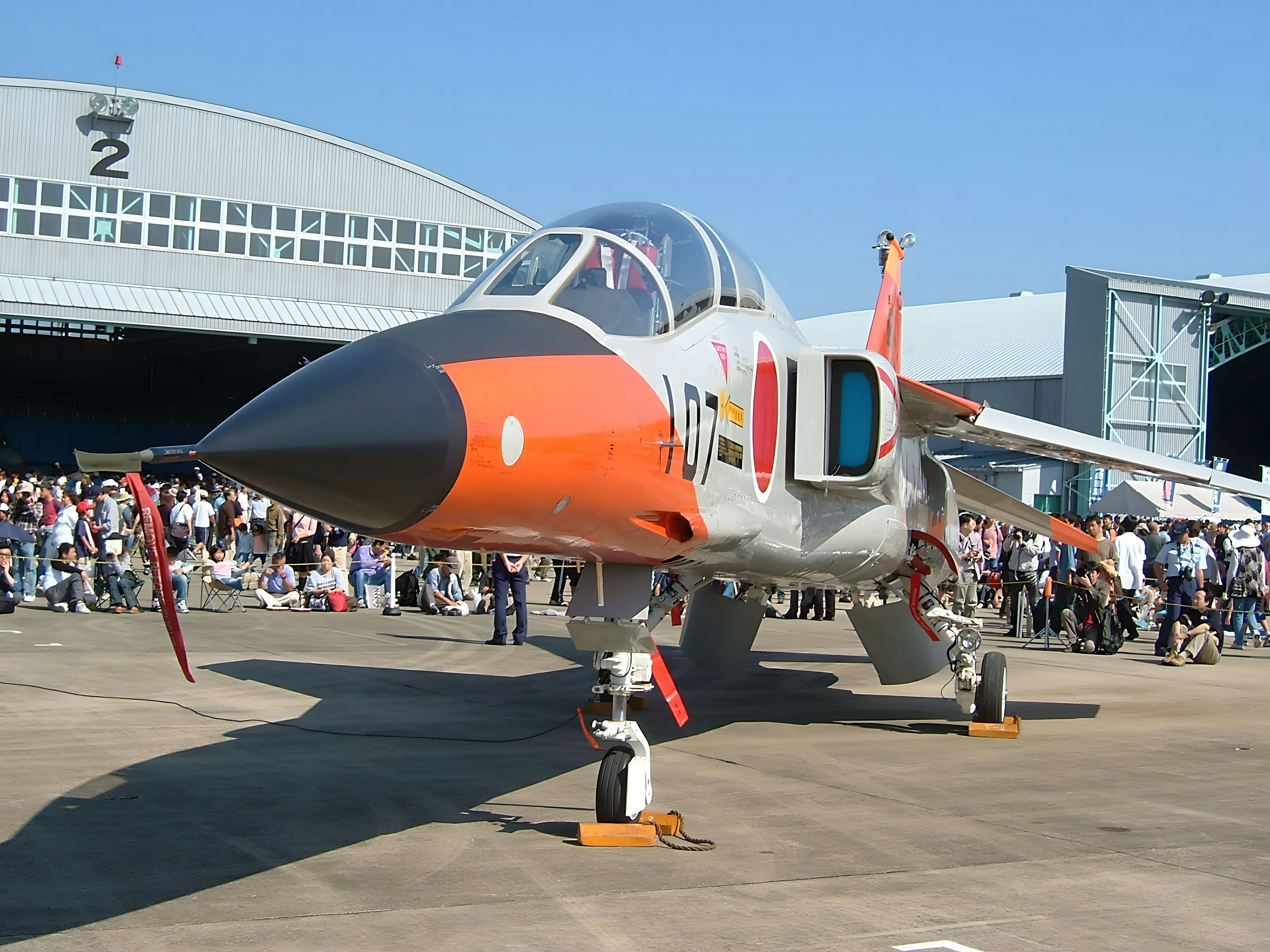 A military aircraft on display at an airshow with a crowd in the background