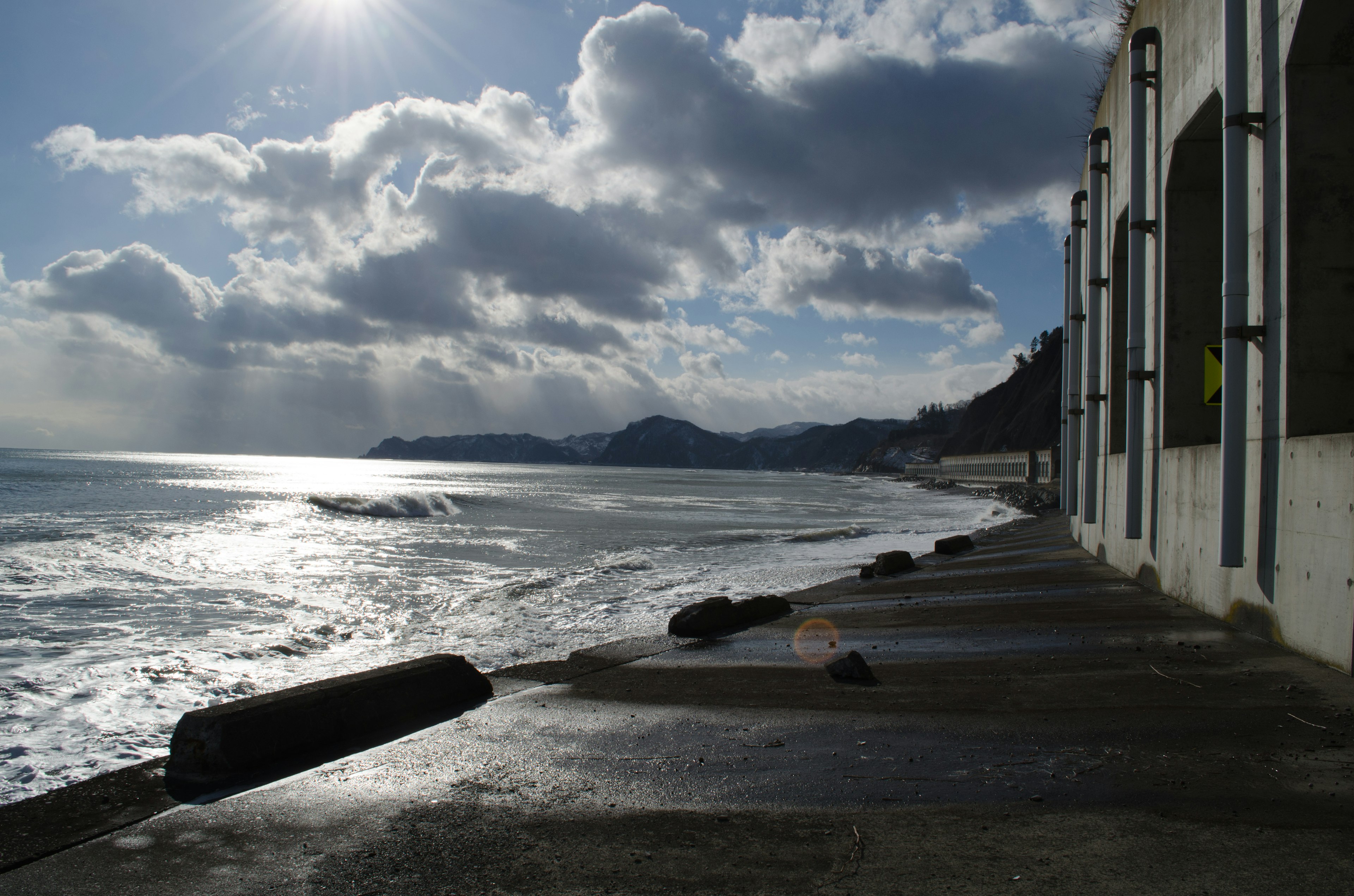 Coastal walkway with waves and clouds Sunlight reflecting on the water