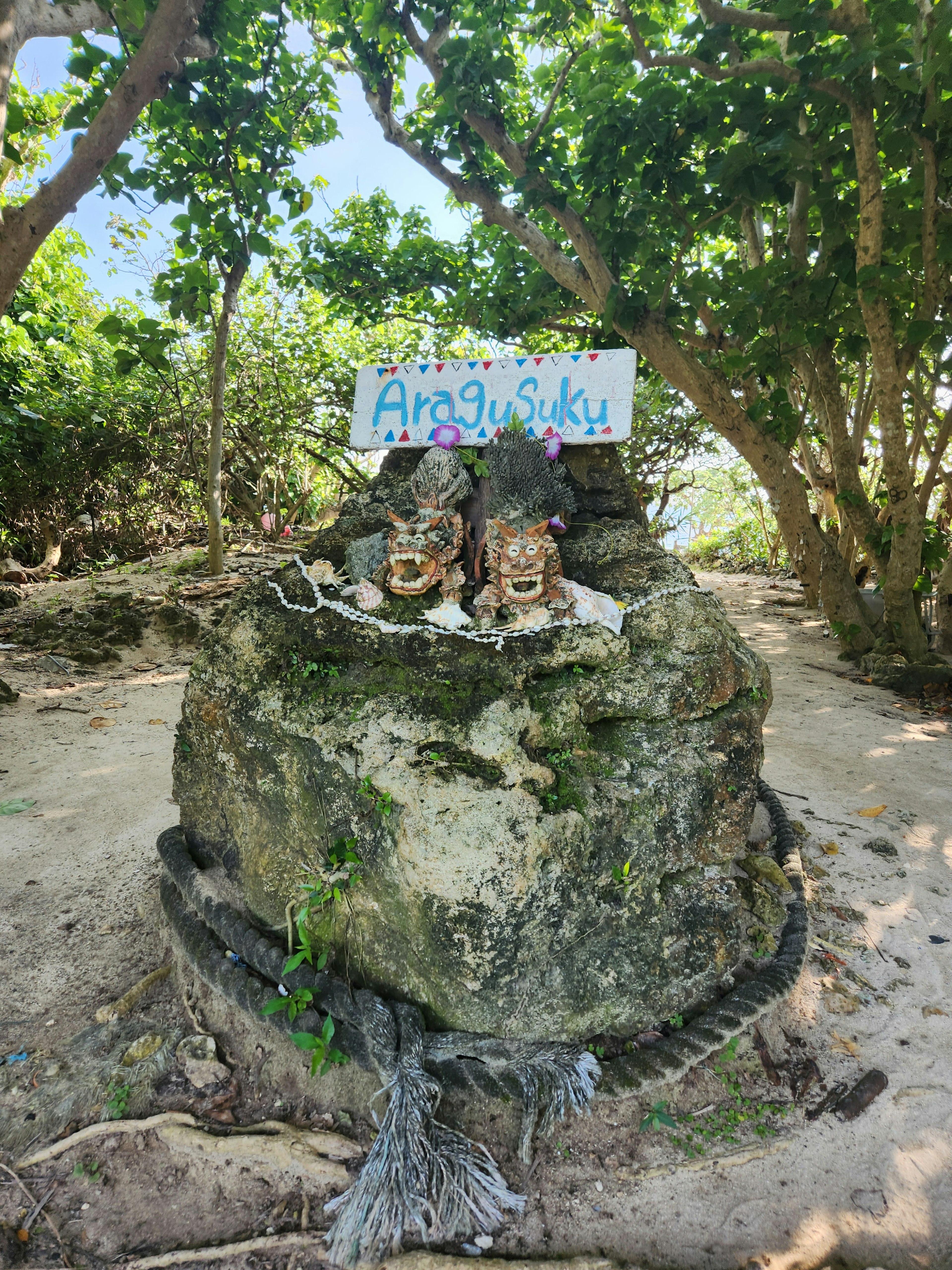 Natürliche Szene mit zwei geschnitzten Gesichtern auf einem Stein und einem bunten Schild darüber