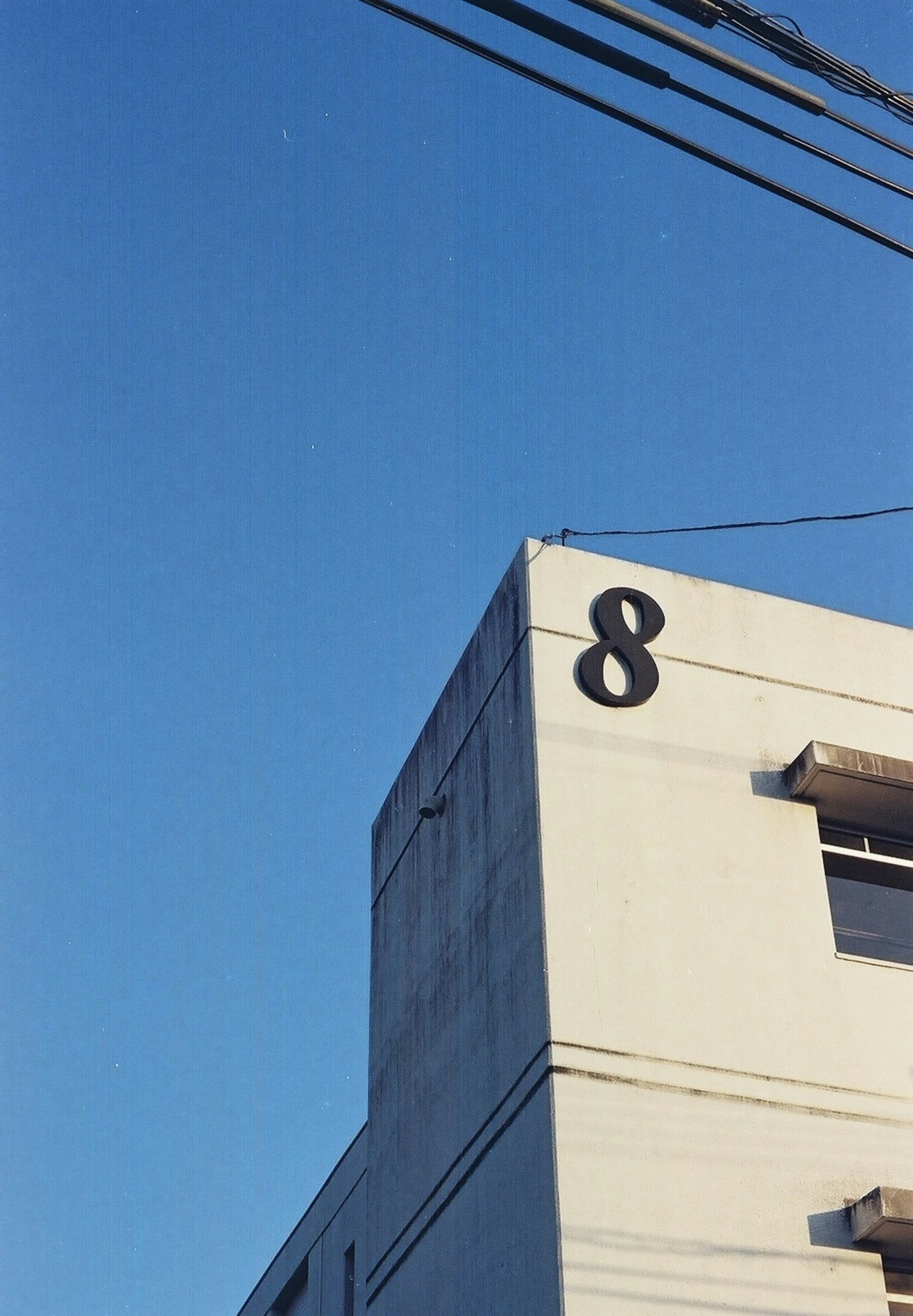 A white building corner with a large number 8 under a blue sky