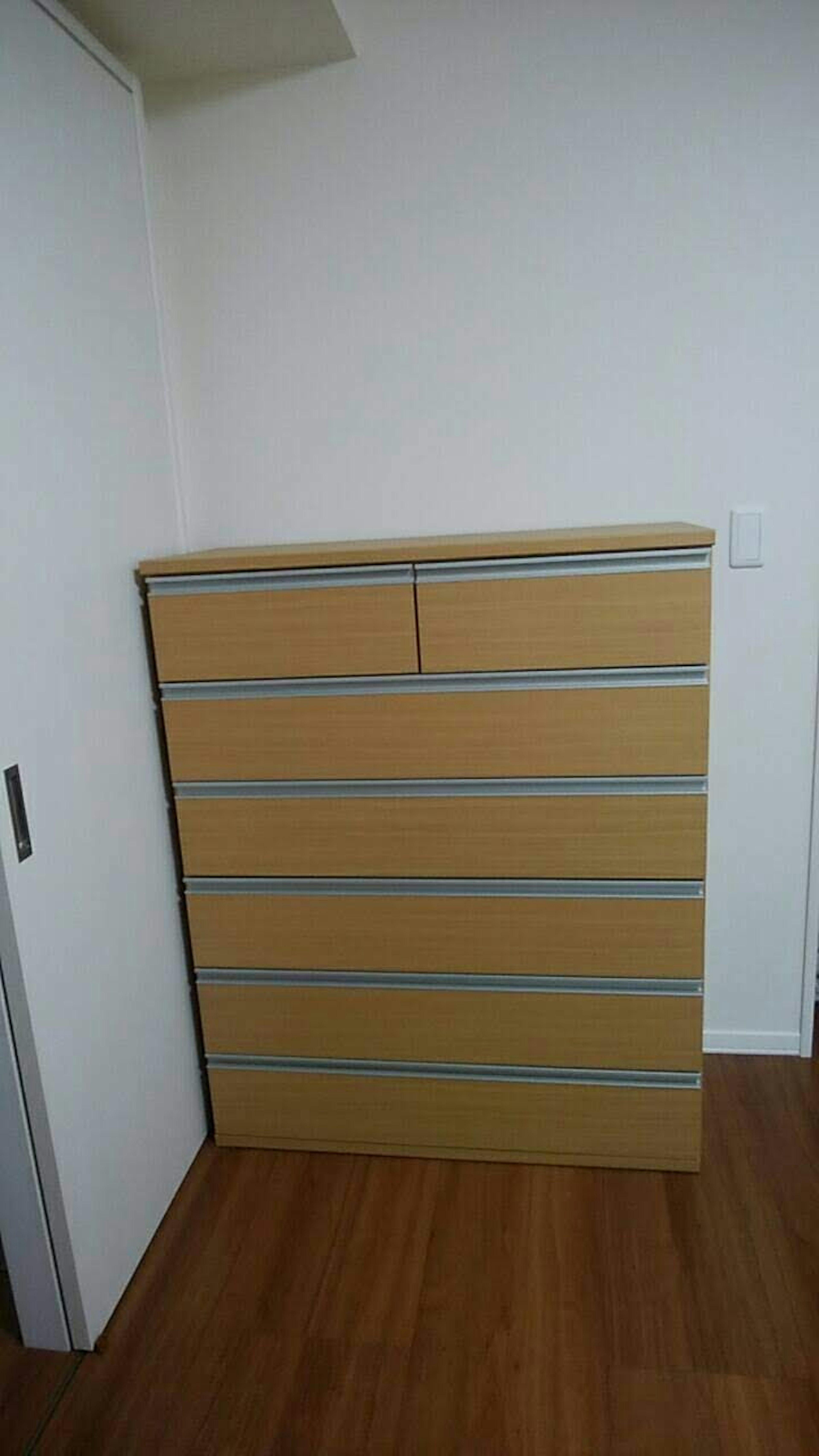 Ein Holzschrank mit Schubladen, der an einer Wand steht