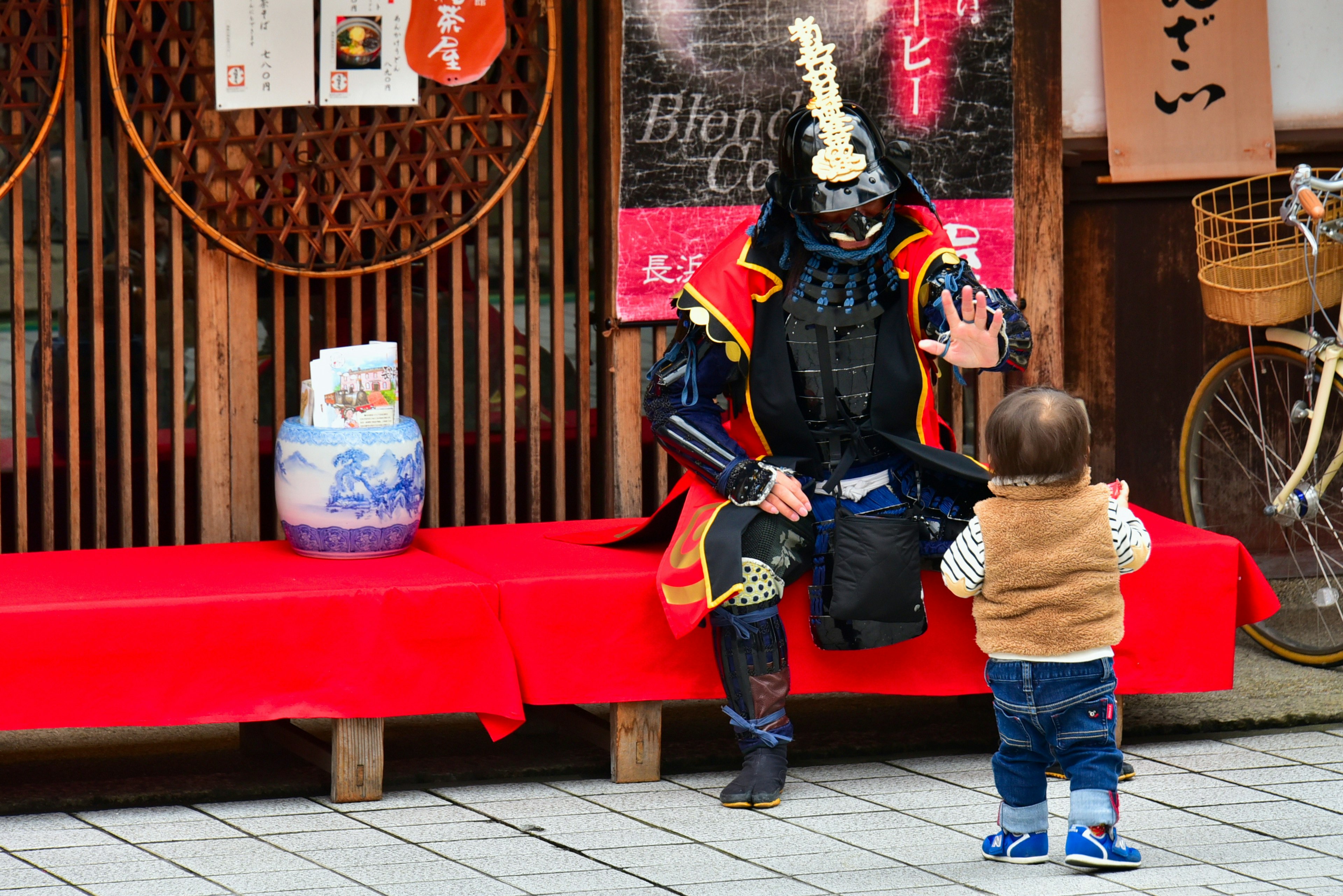 A child interacting with a person dressed as a samurai