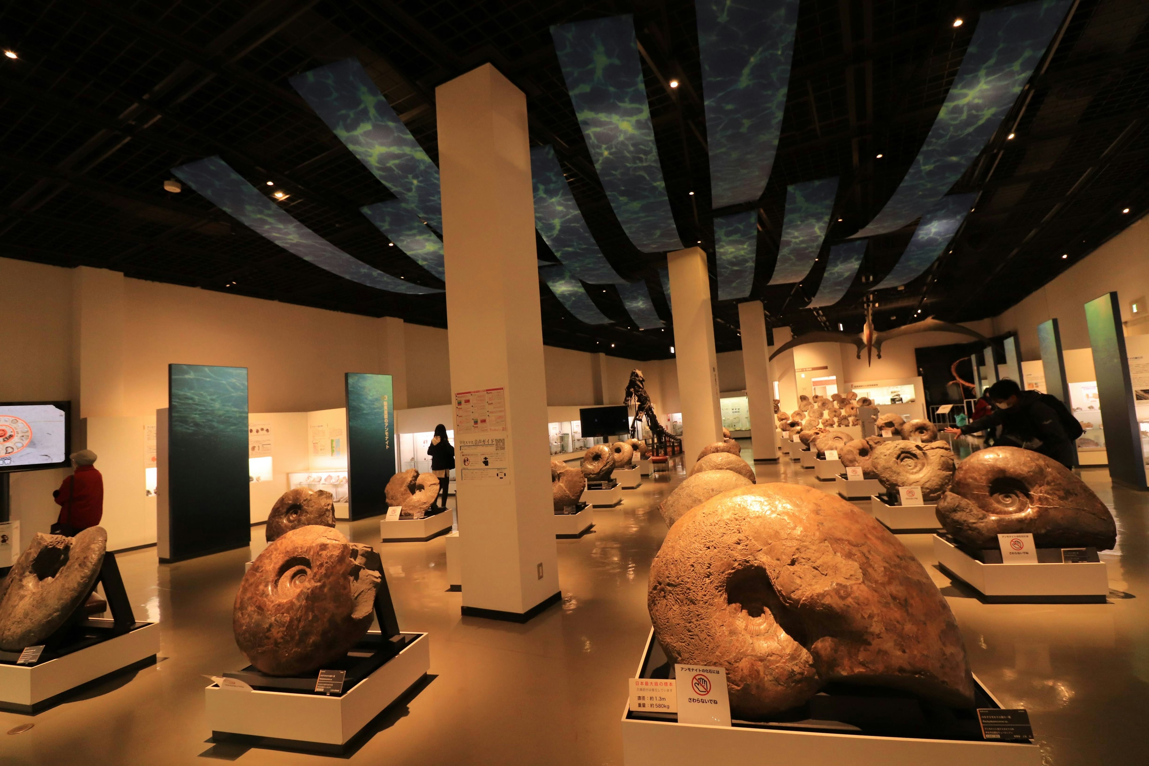 Large sculptures on display in an exhibition hall with decorative ceiling