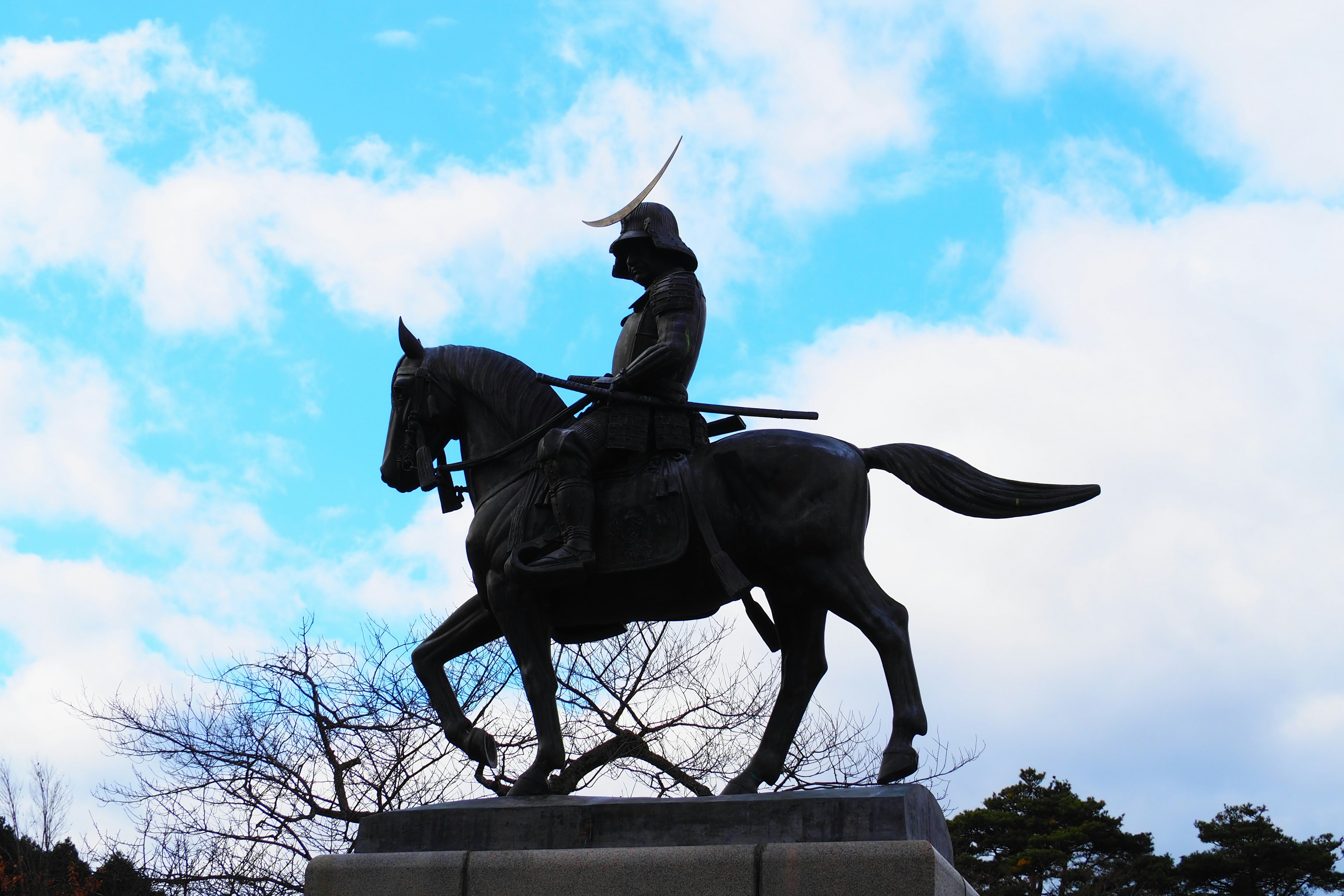 Bronze statue of a mounted samurai against a blue sky