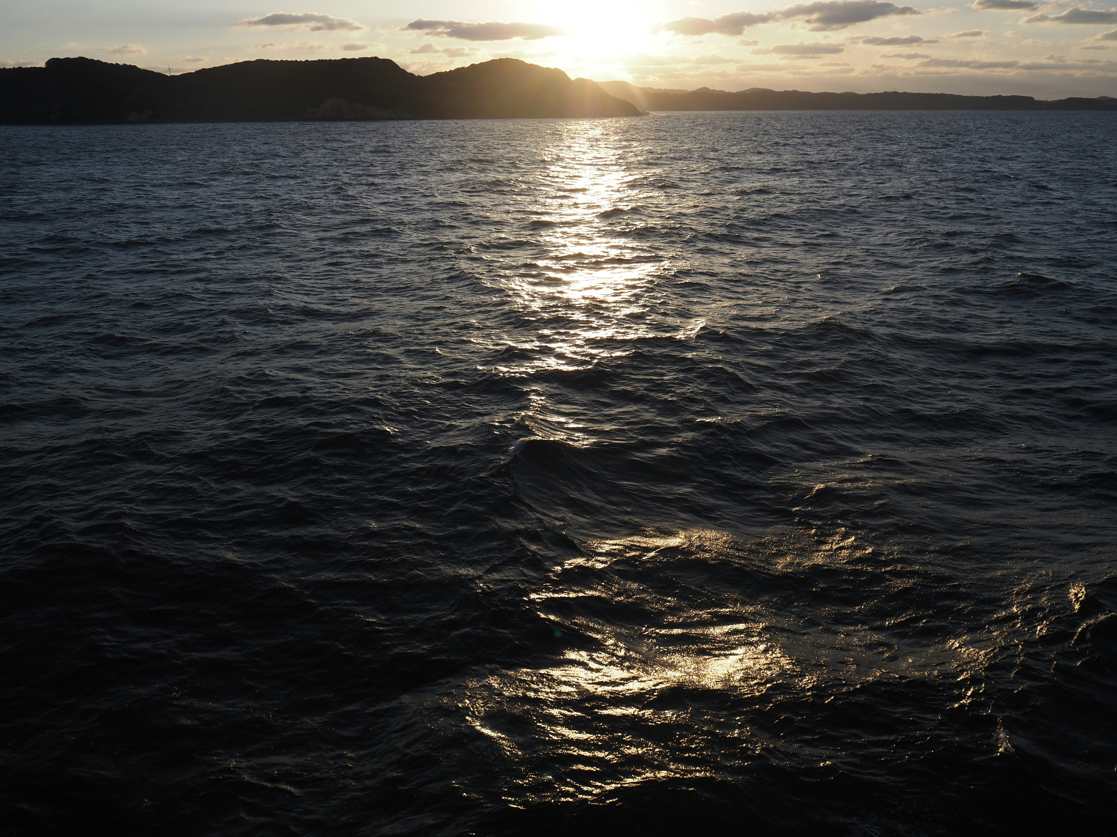 Atardecer sobre el océano con olas tranquilas que reflejan la luz