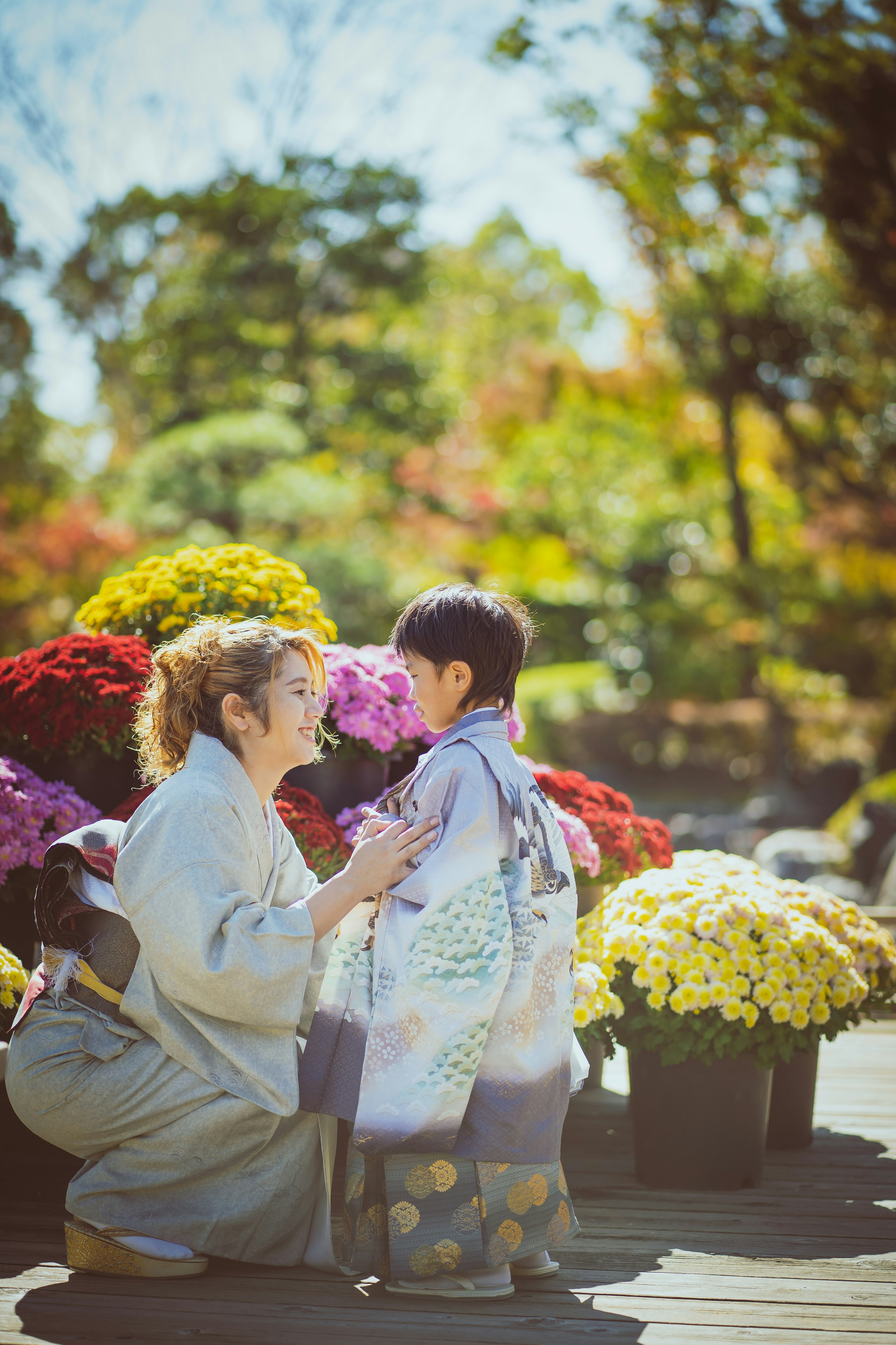 秋の花々に囲まれた女性と子供が笑顔で会話しているシーン