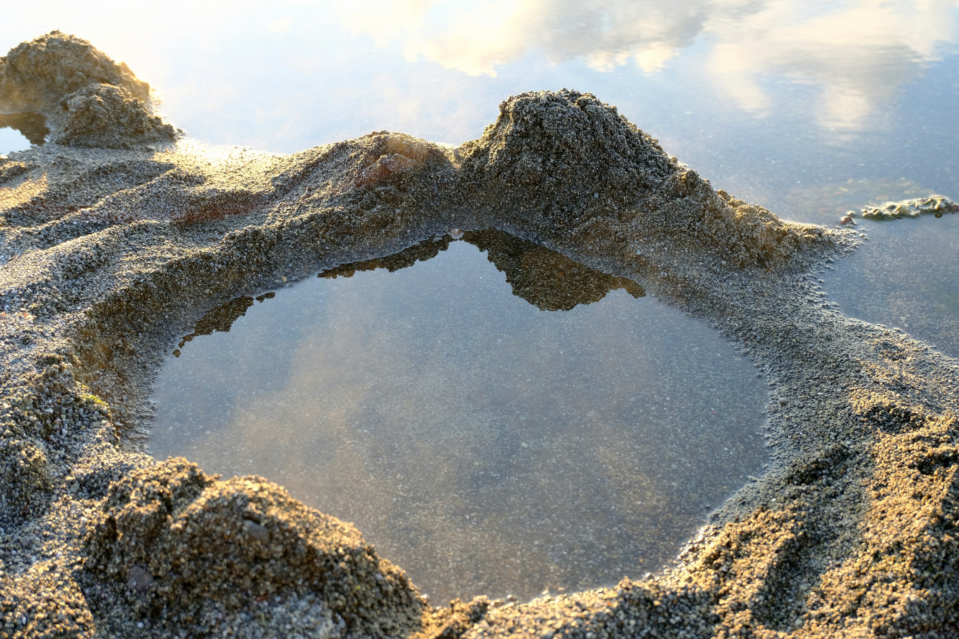 Image capturant une flaque d'eau sur un terrain sablonneux avec des textures uniques