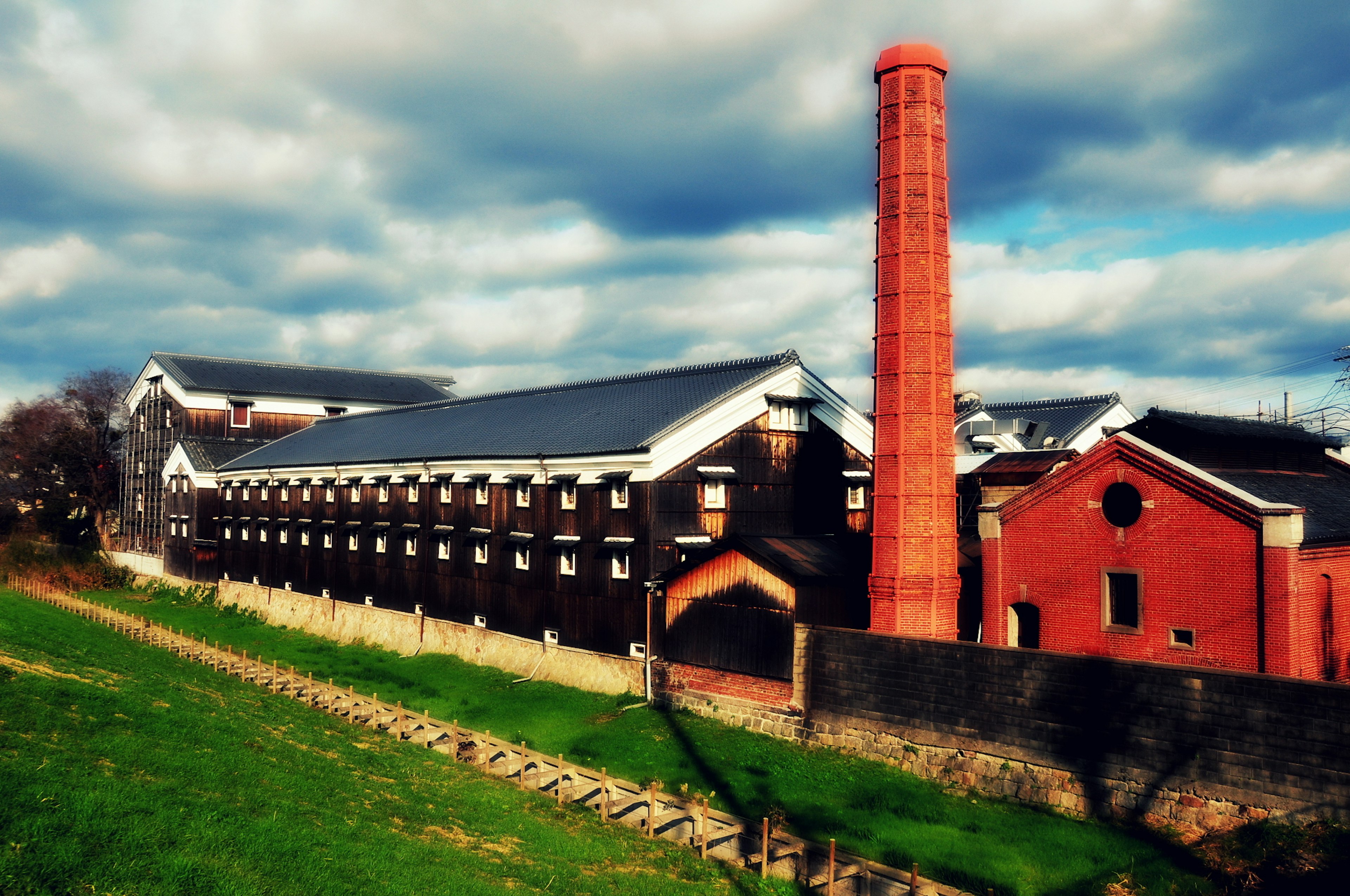 Industrielles Gebäude mit rotem Schornstein vor einem bewölkten Himmel