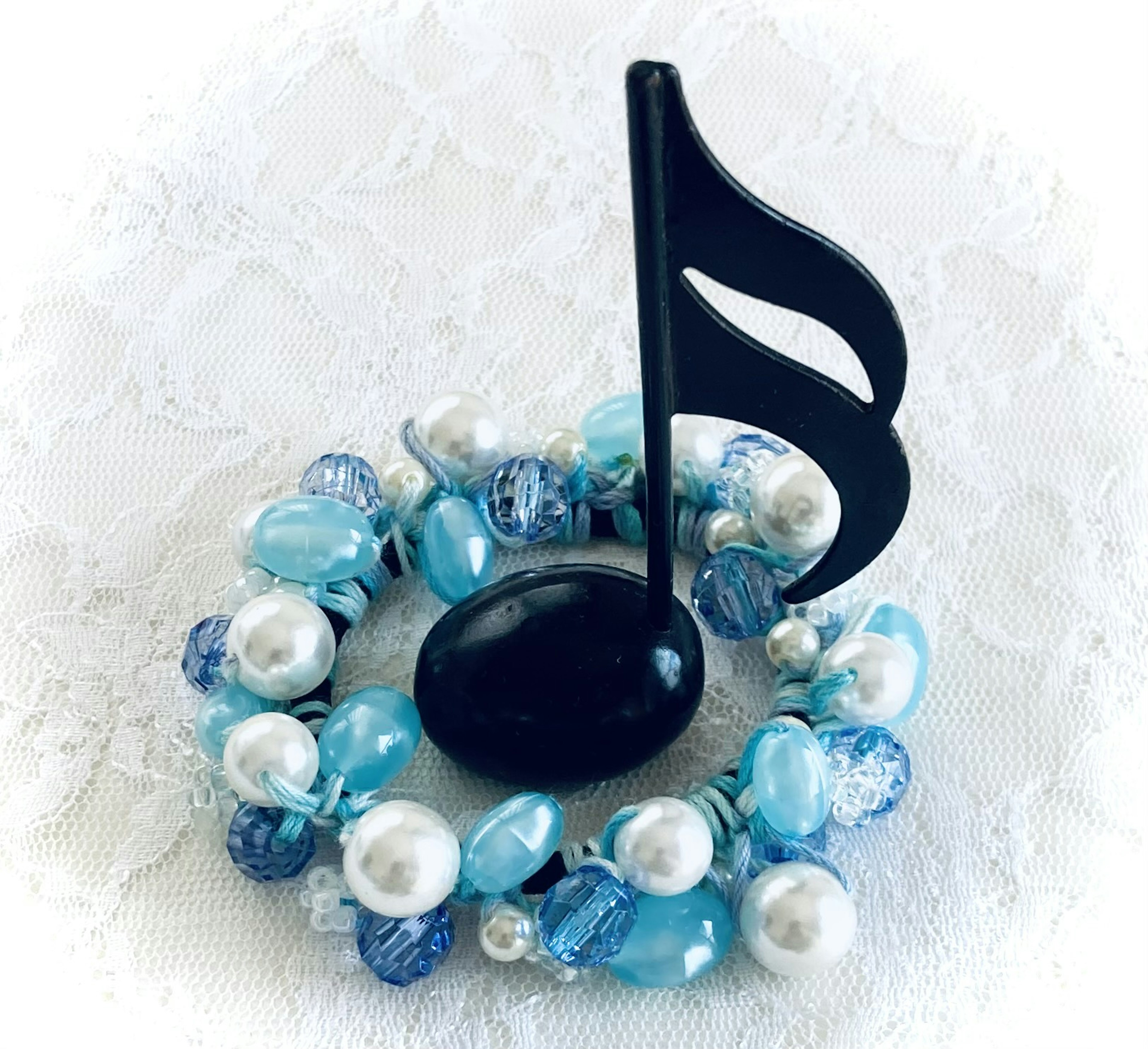 Decorative wreath made of blue beads and pearls with a black musical note figurine in the center