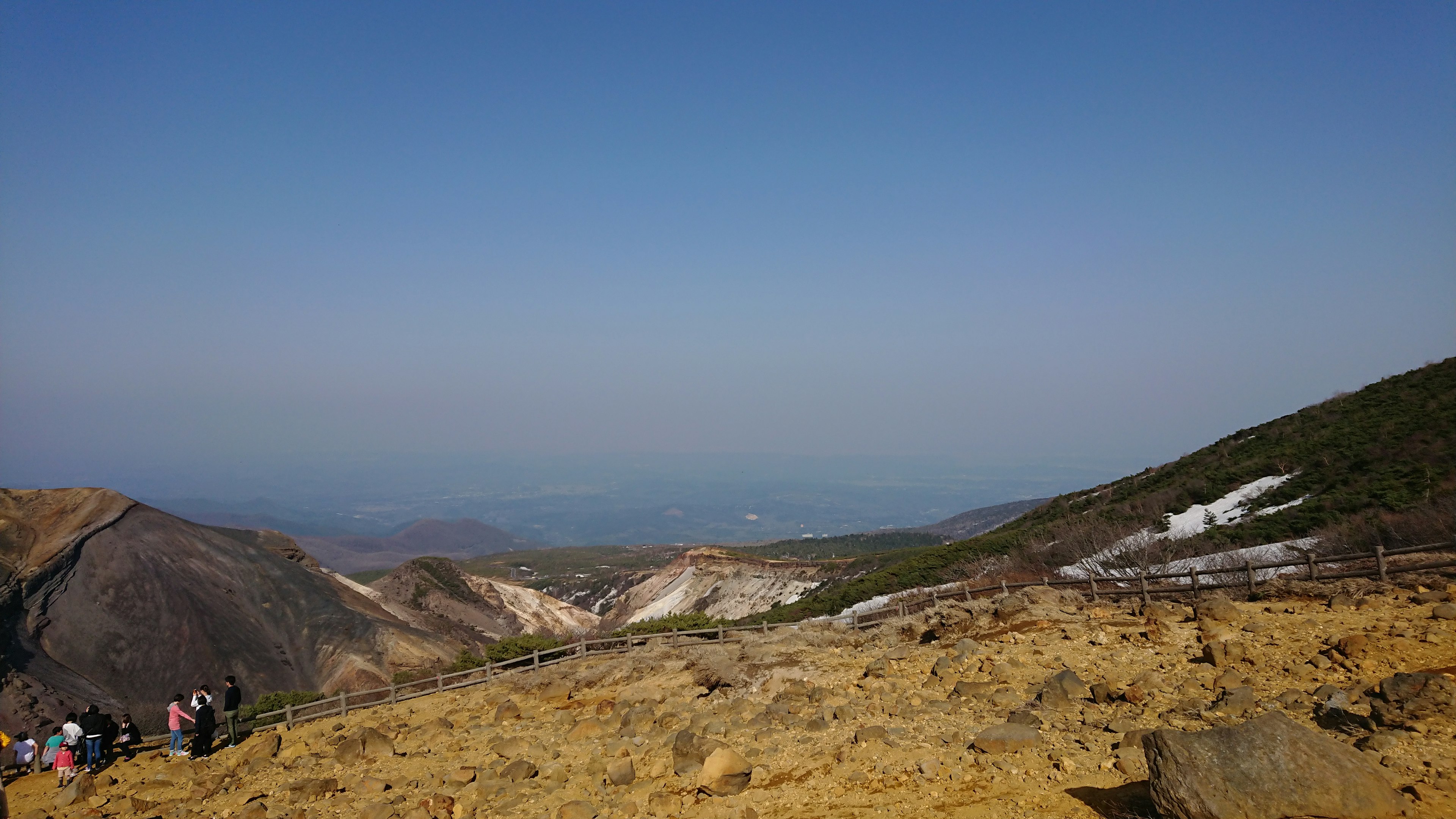 青い空と乾燥した草原の風景に人々が集まる山の景色