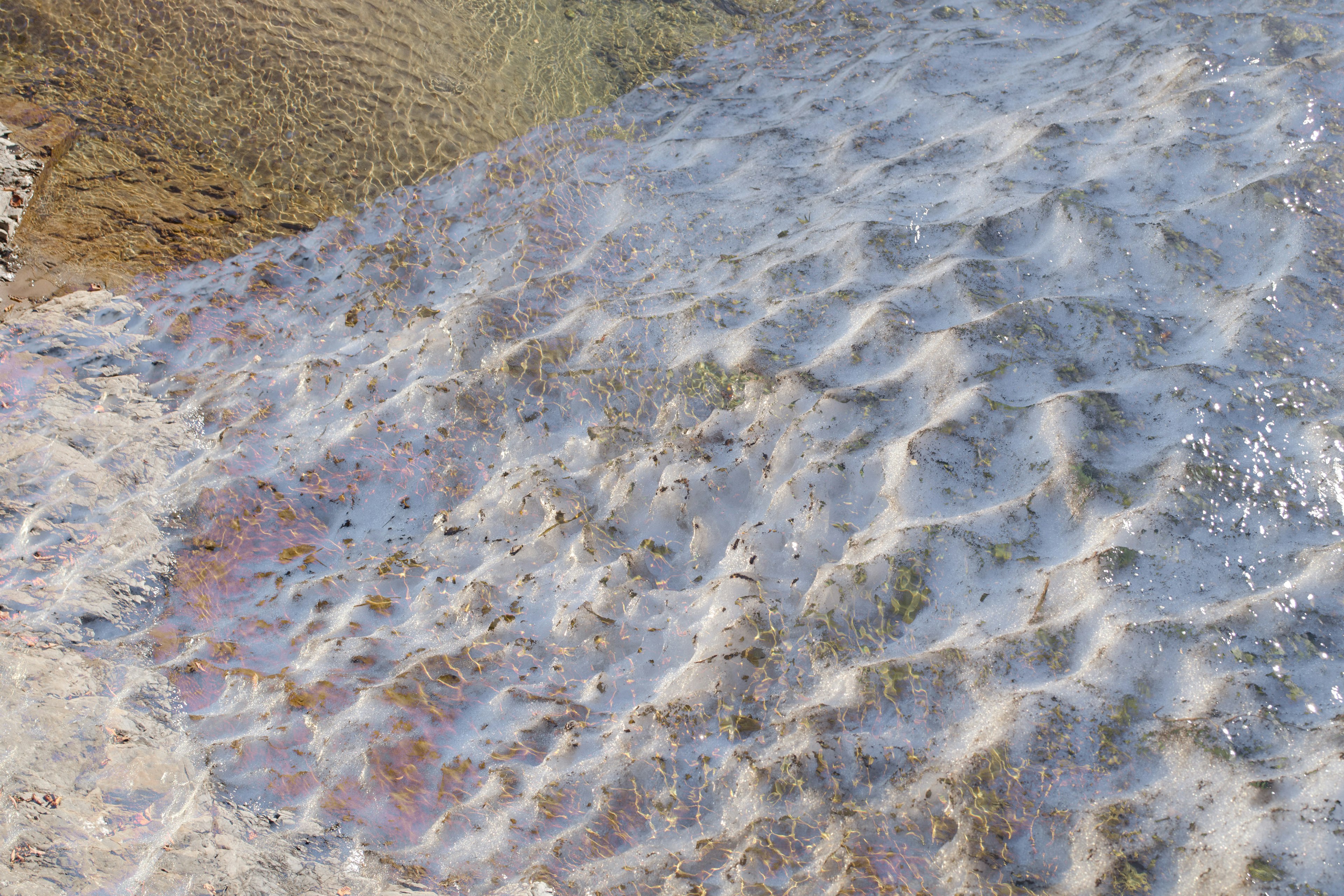 Primo piano dell'acqua increspata su una spiaggia di sabbia