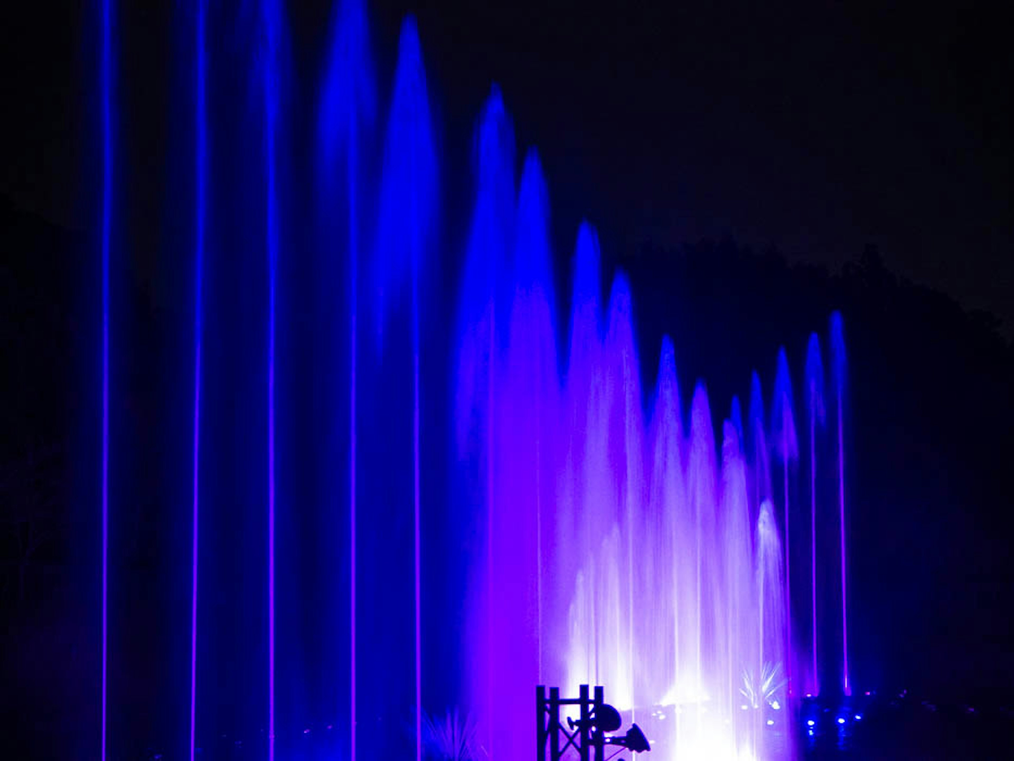 Espectáculo de fuentes nocturno con chorros de agua iluminados en azul y púrpura