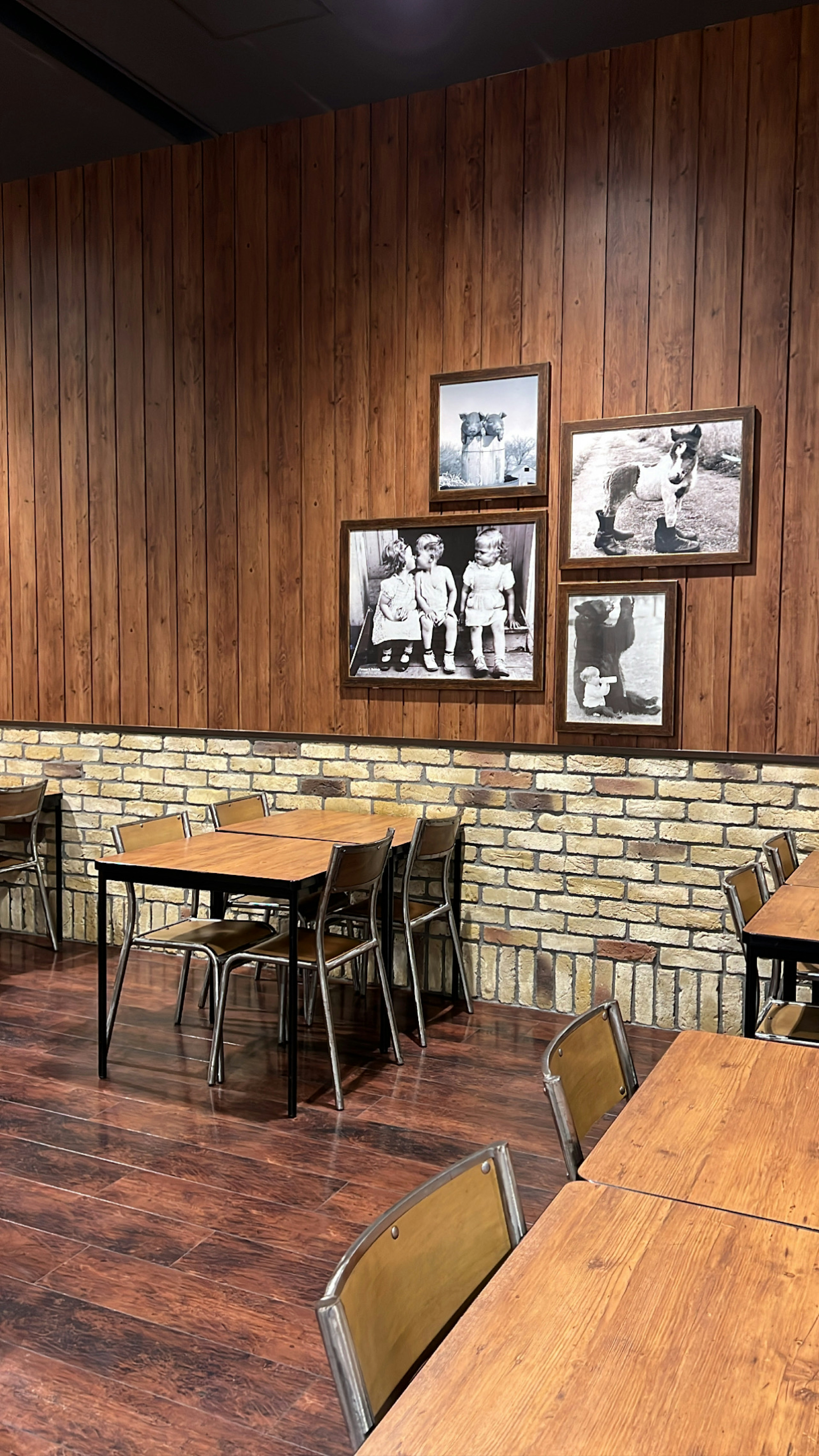 Innenansicht eines gemütlichen Cafés mit HolzWänden und BacksteinAkzenten Schwarzweiße Fotos schmücken die Wand