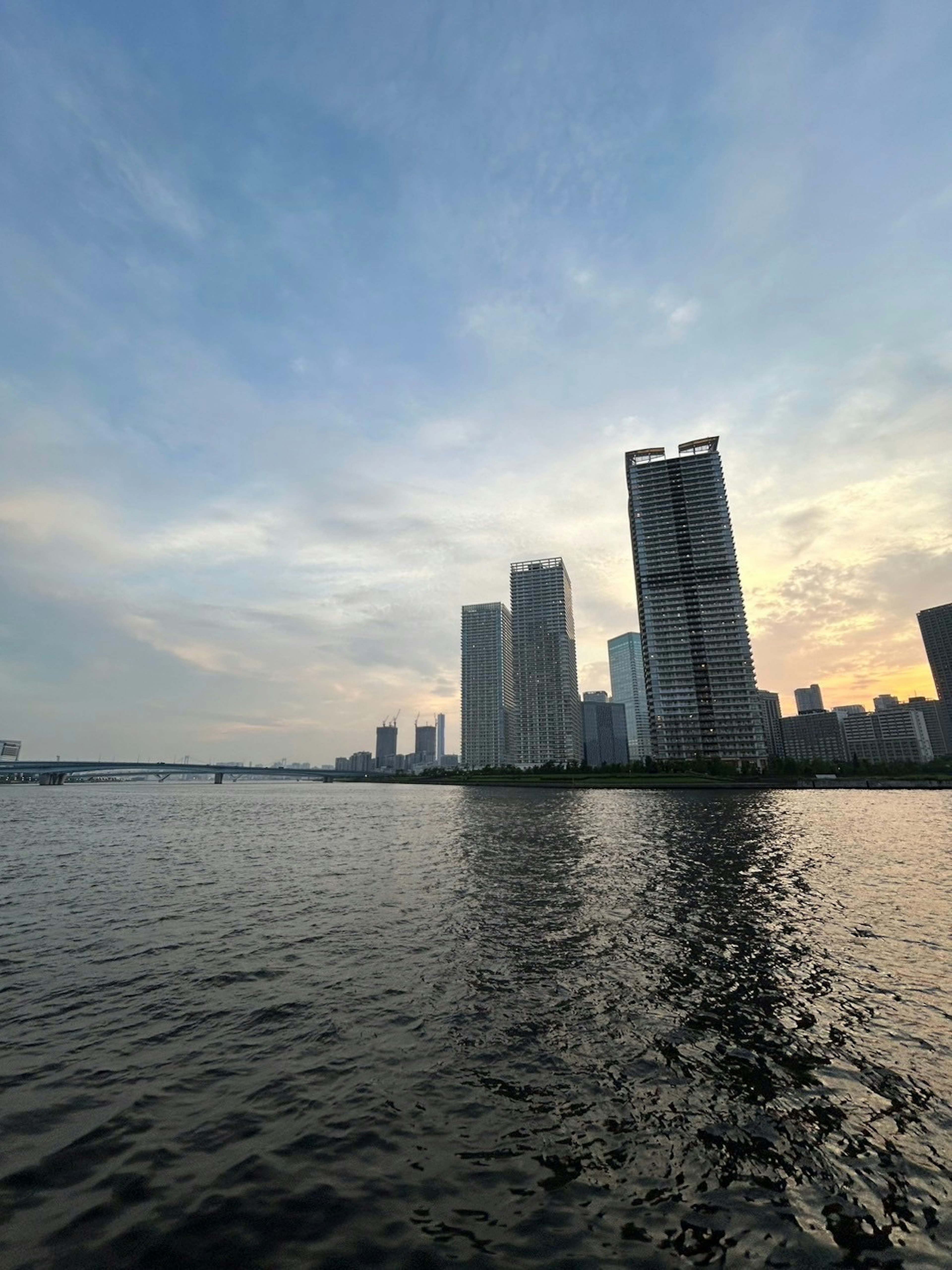 Pemandangan matahari terbenam dengan gedung pencakar langit dan refleksi di air