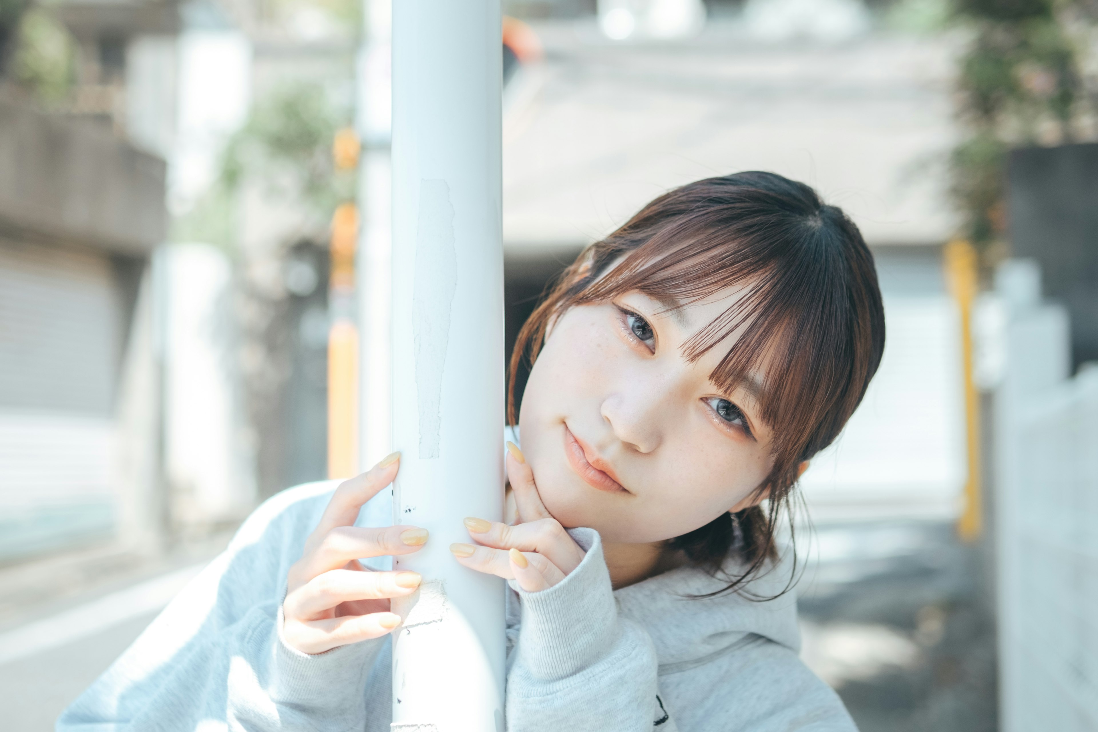 Portrait of a woman leaning against a pole in the street with a gentle expression and natural light