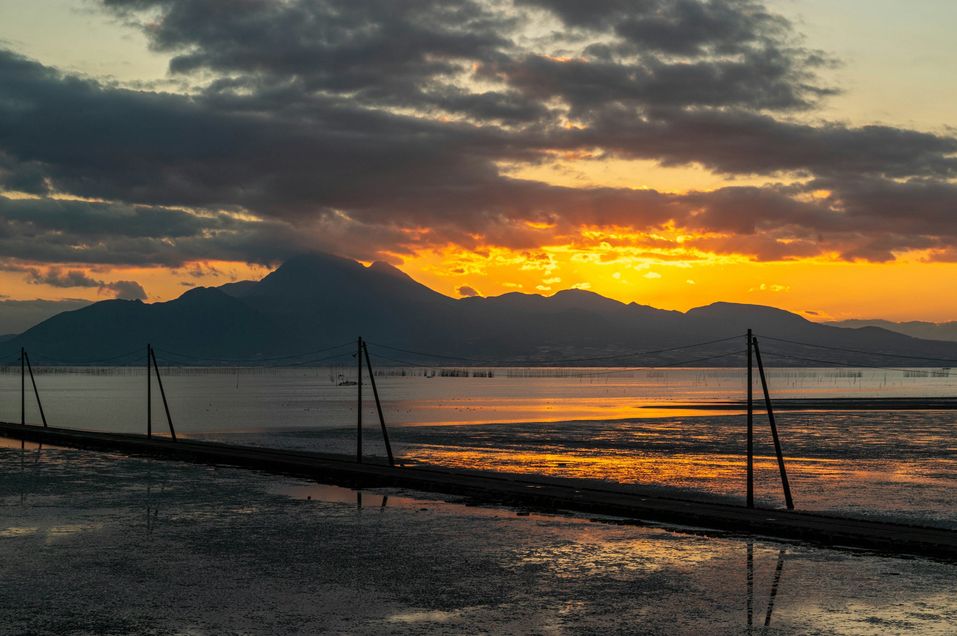 Atardecer reflejándose en el agua con montañas al fondo