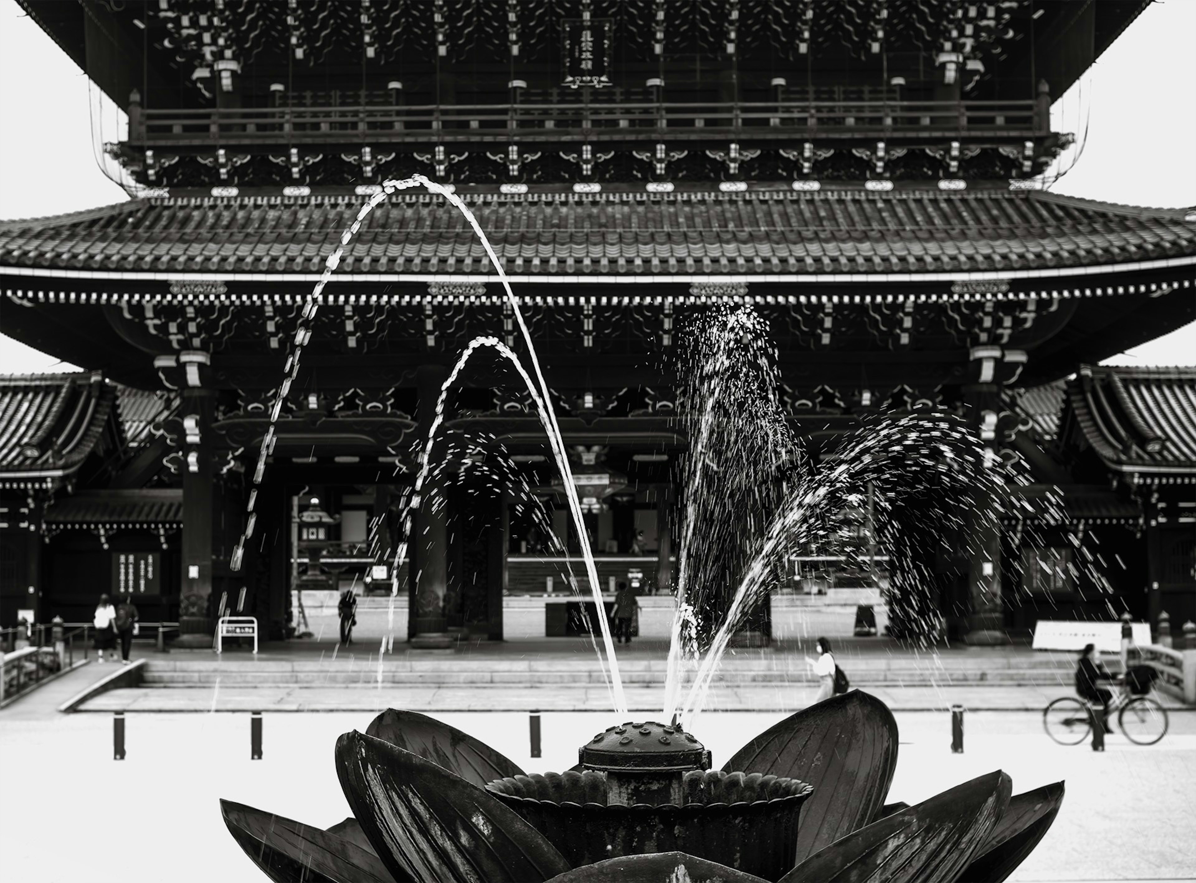 A black and white image featuring a beautiful fountain and temple architecture