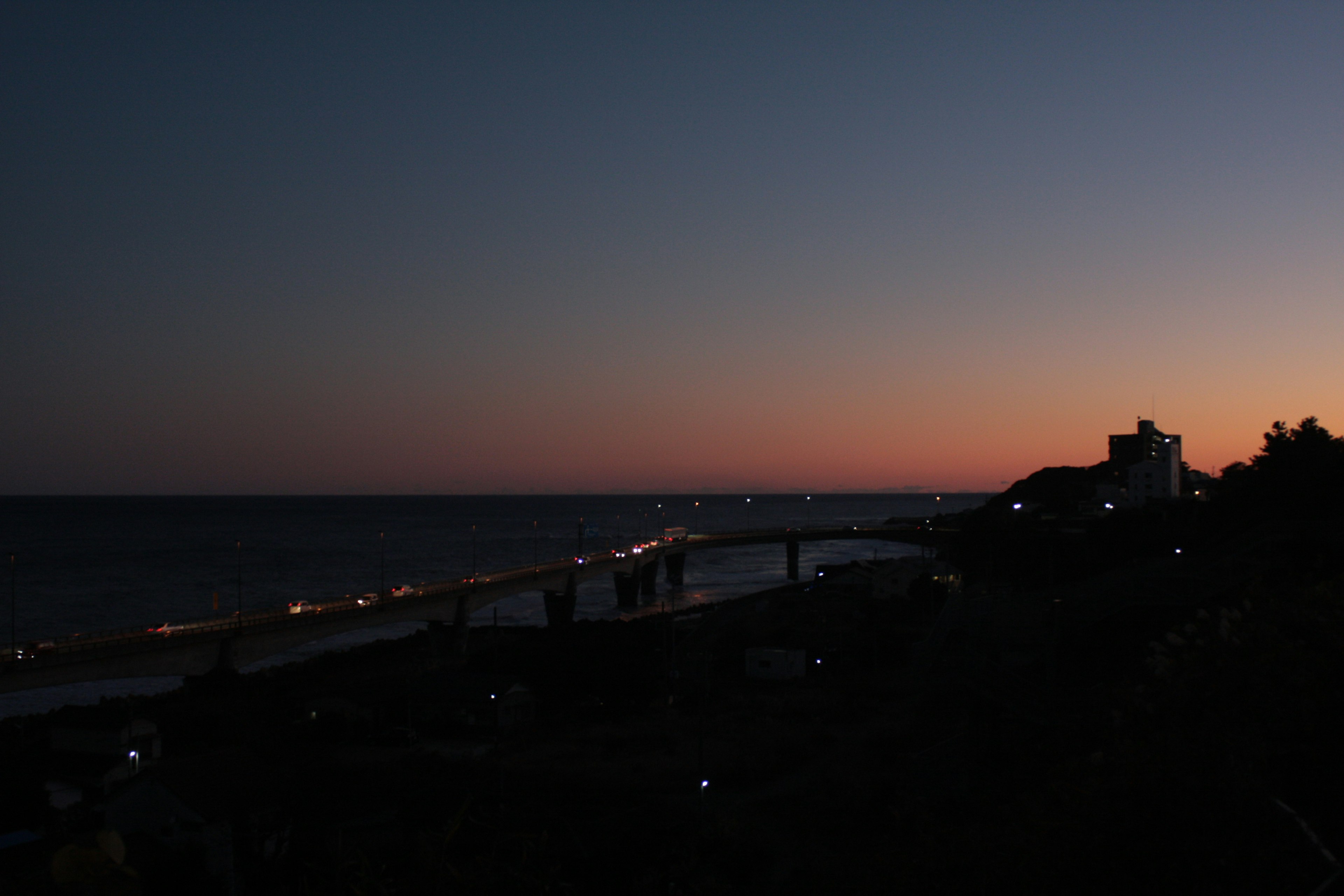 Vista costera al atardecer con luces a lo largo del puente