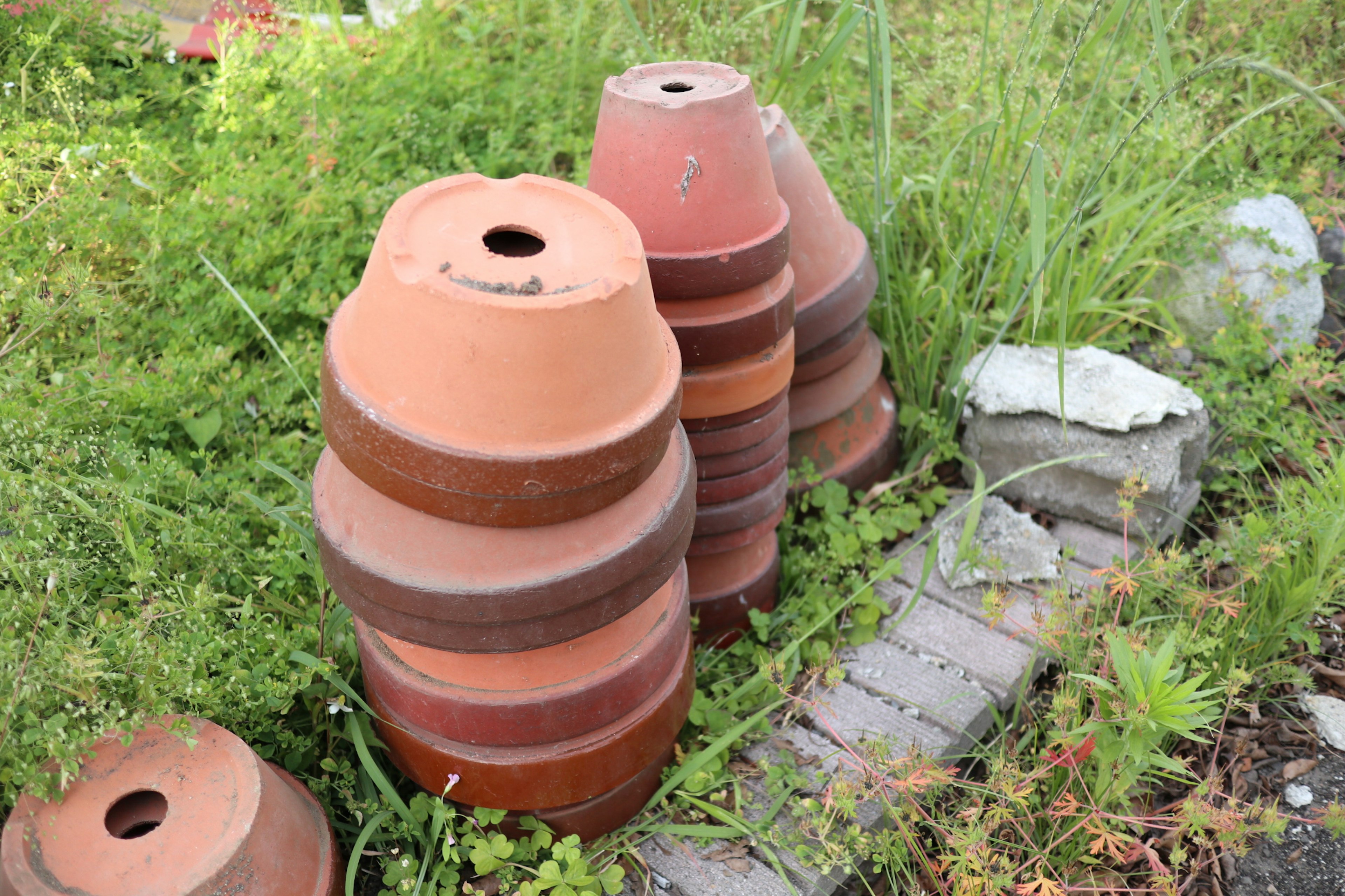 Stacked terracotta pots surrounded by green grass