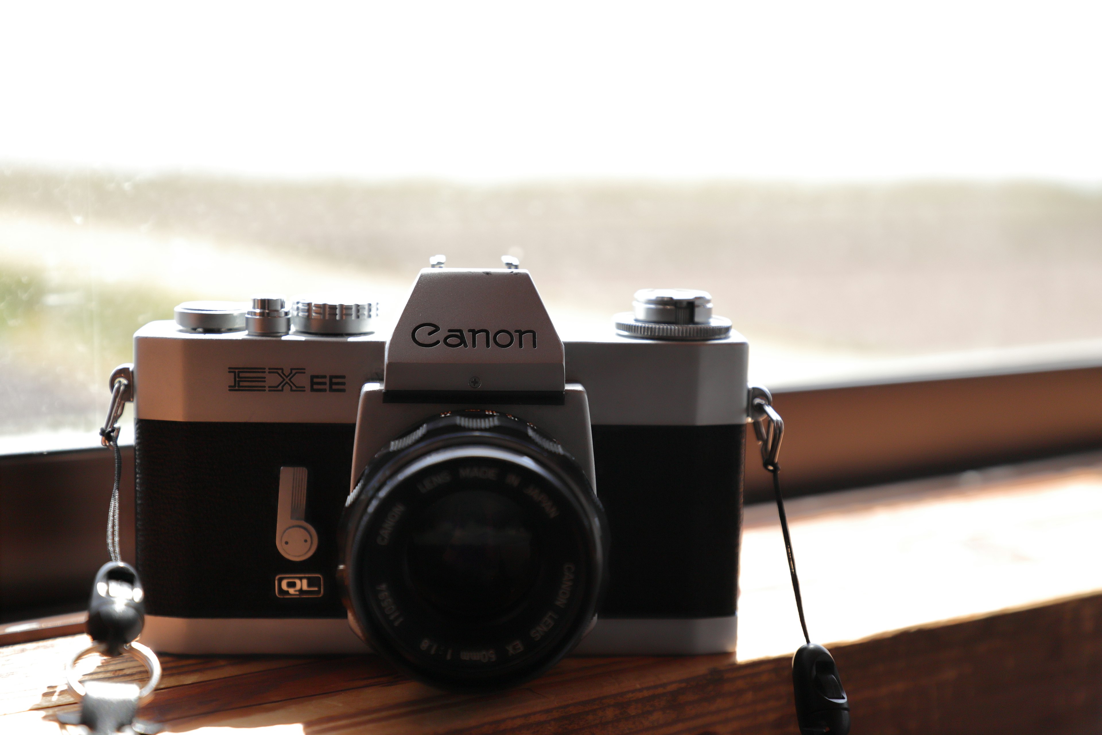 Silver Canon camera placed on a wooden surface by the window